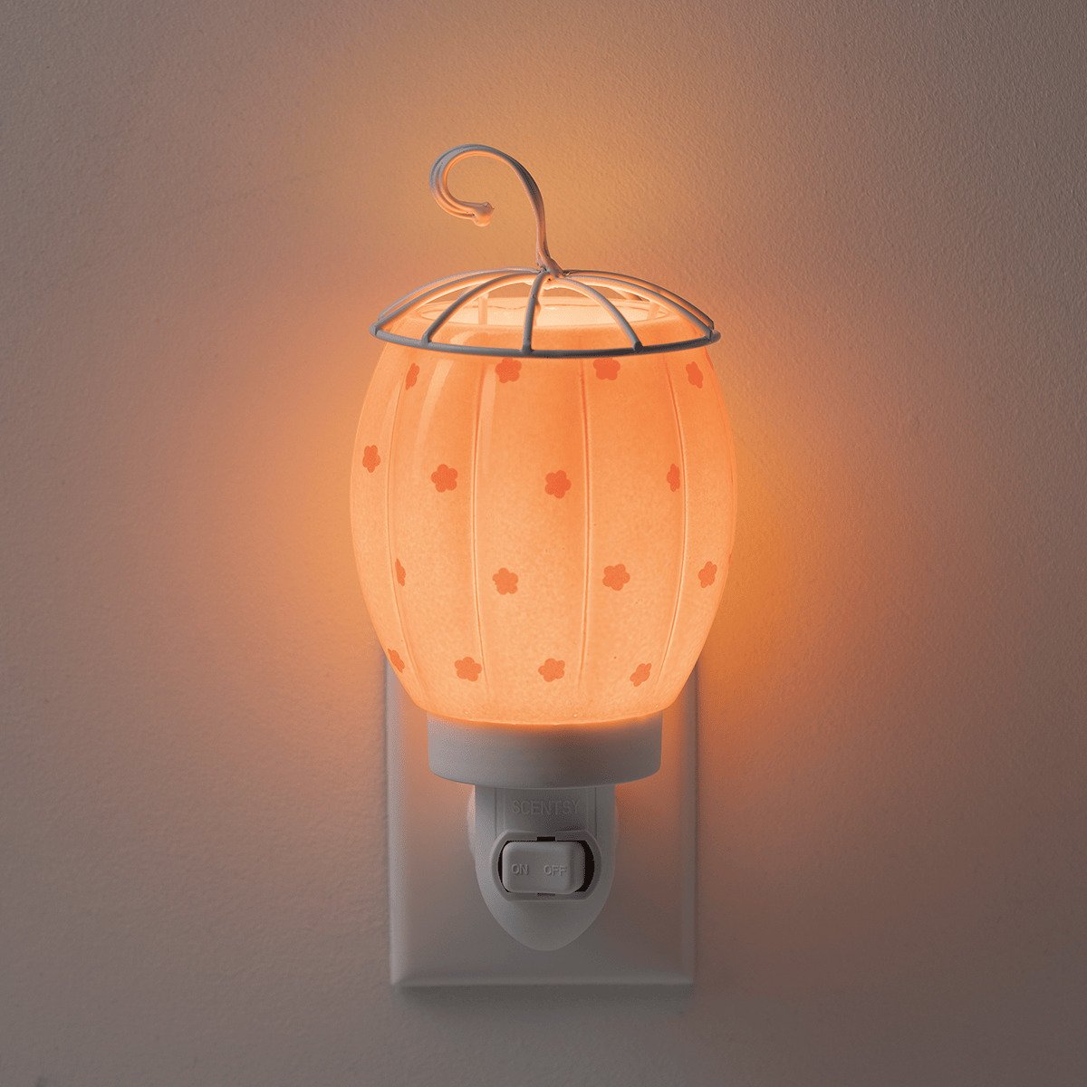 Pumpkin Posy Scentsy Mini Warmer glowing warmly against a dark background