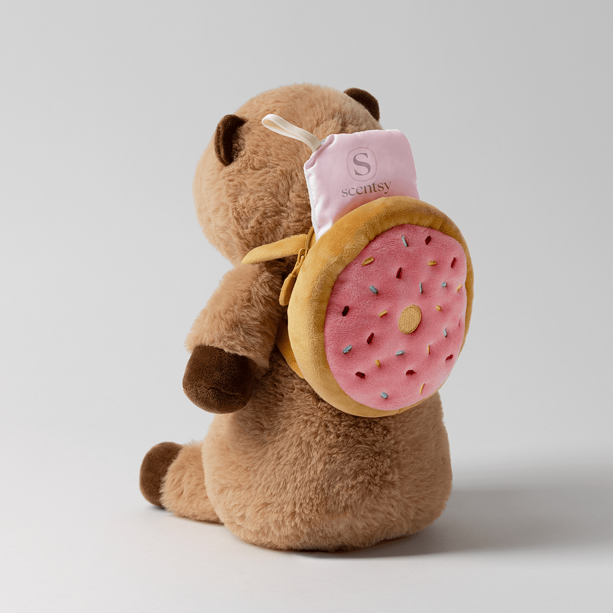 Crumb the Capybara Scentsy Buddy with pink sprinkled donut backpack and Scentsy Scent Pak