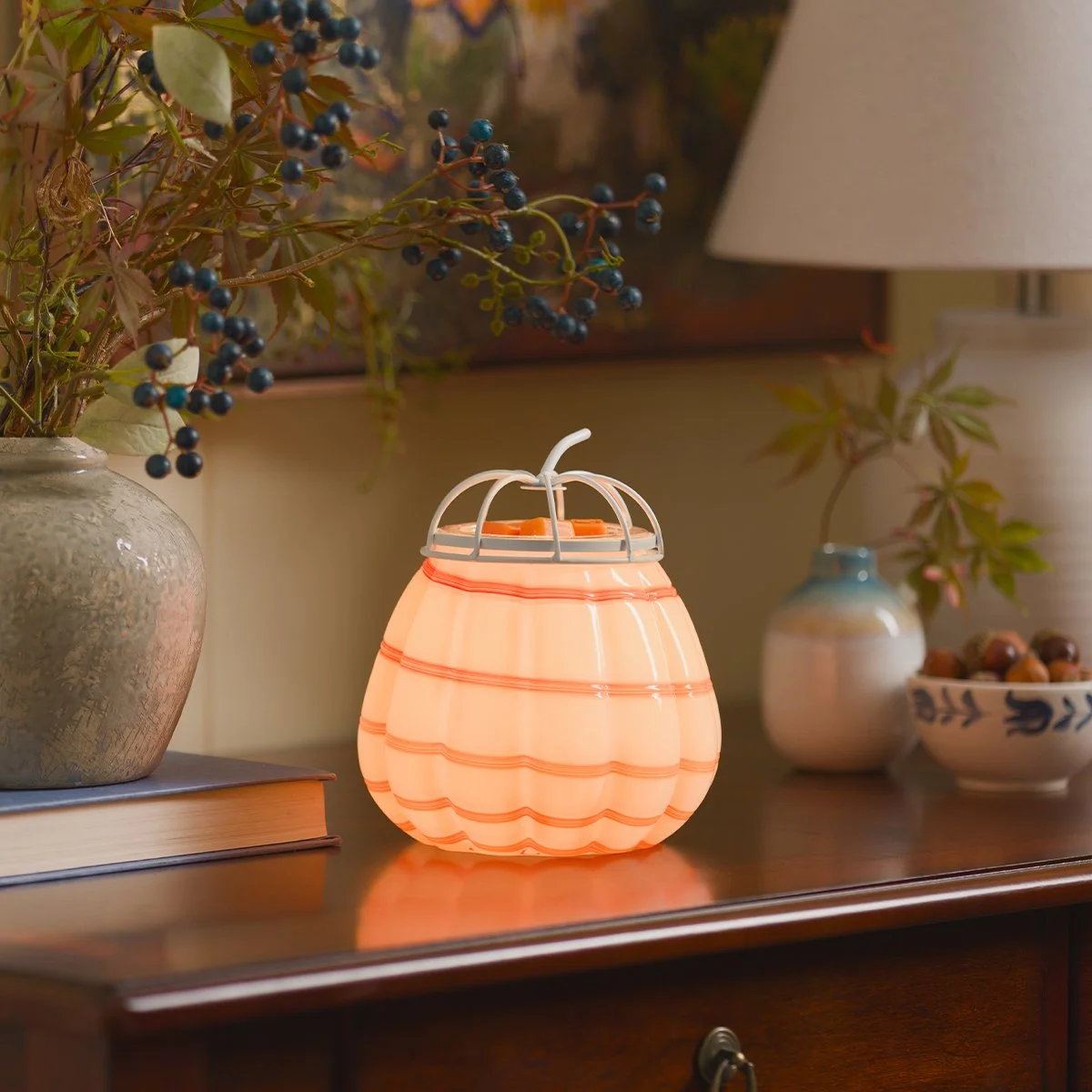 Scentsy Cider Swirl Warmer glowing on a wooden table with autumn décor, berries and cozy fall accents from the Harvest Collection