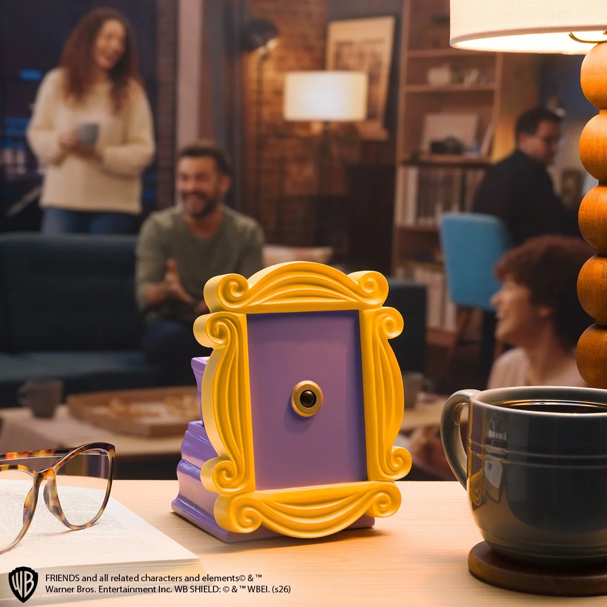 Friends The One With the Yellow Frame Scentsy Warmer glowing on a cozy coffee table beside a mug and reading glasses in a warm living room setting.