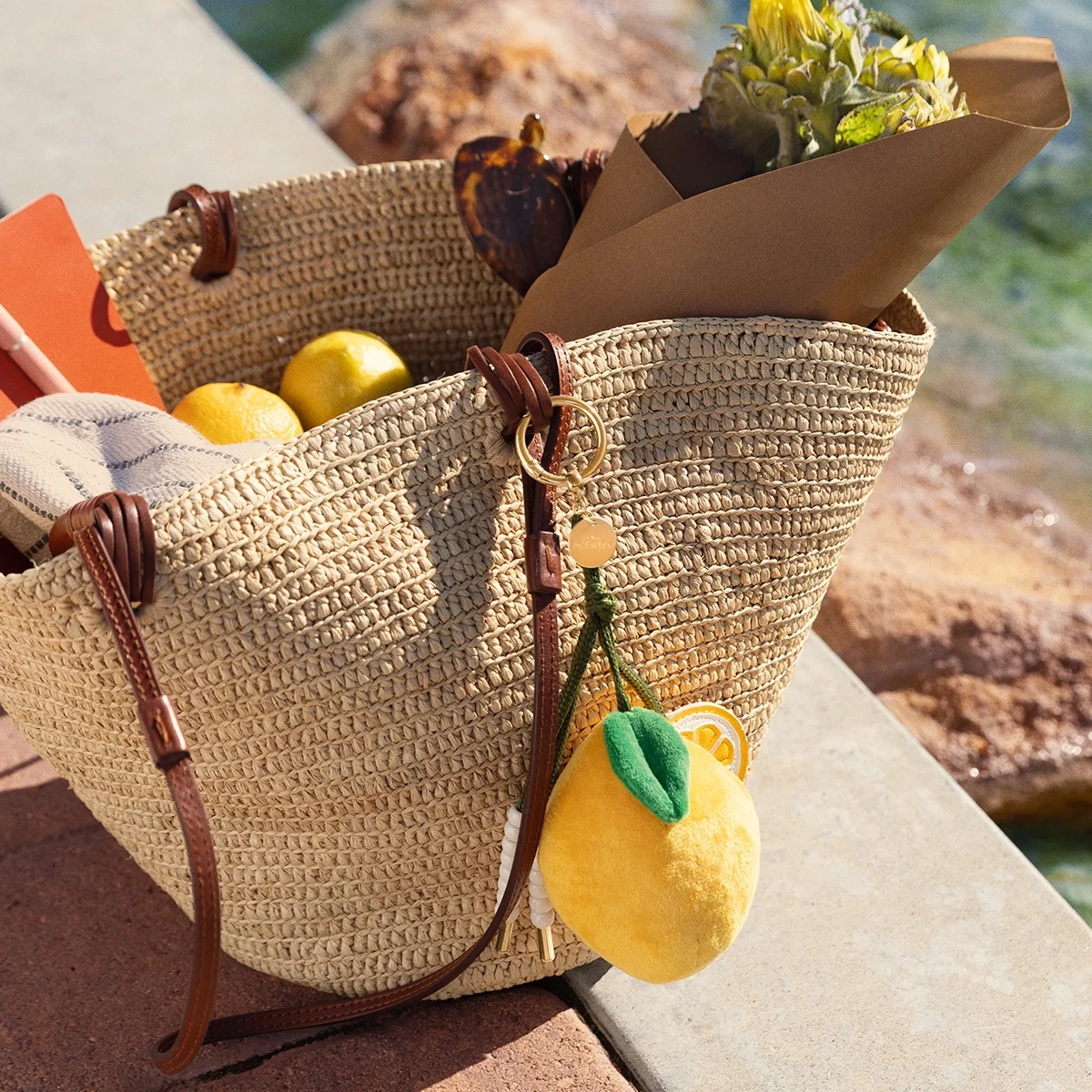 Sorrento Lemon Scentsy Charm Clip attached to a woven beach tote, inspired by the sunny citrus charm of Italy and scented with the Sparkling Yellow fragrance