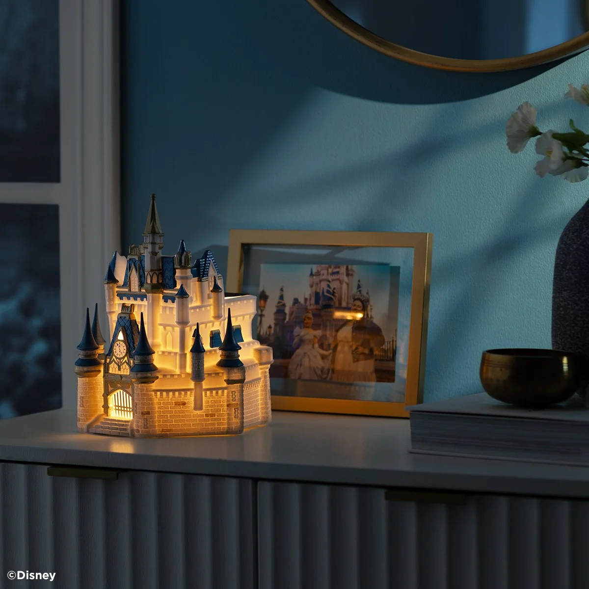 The glowing Cinderella Castle Scentsy Warmer styled in a dim room for a cozy Disney display