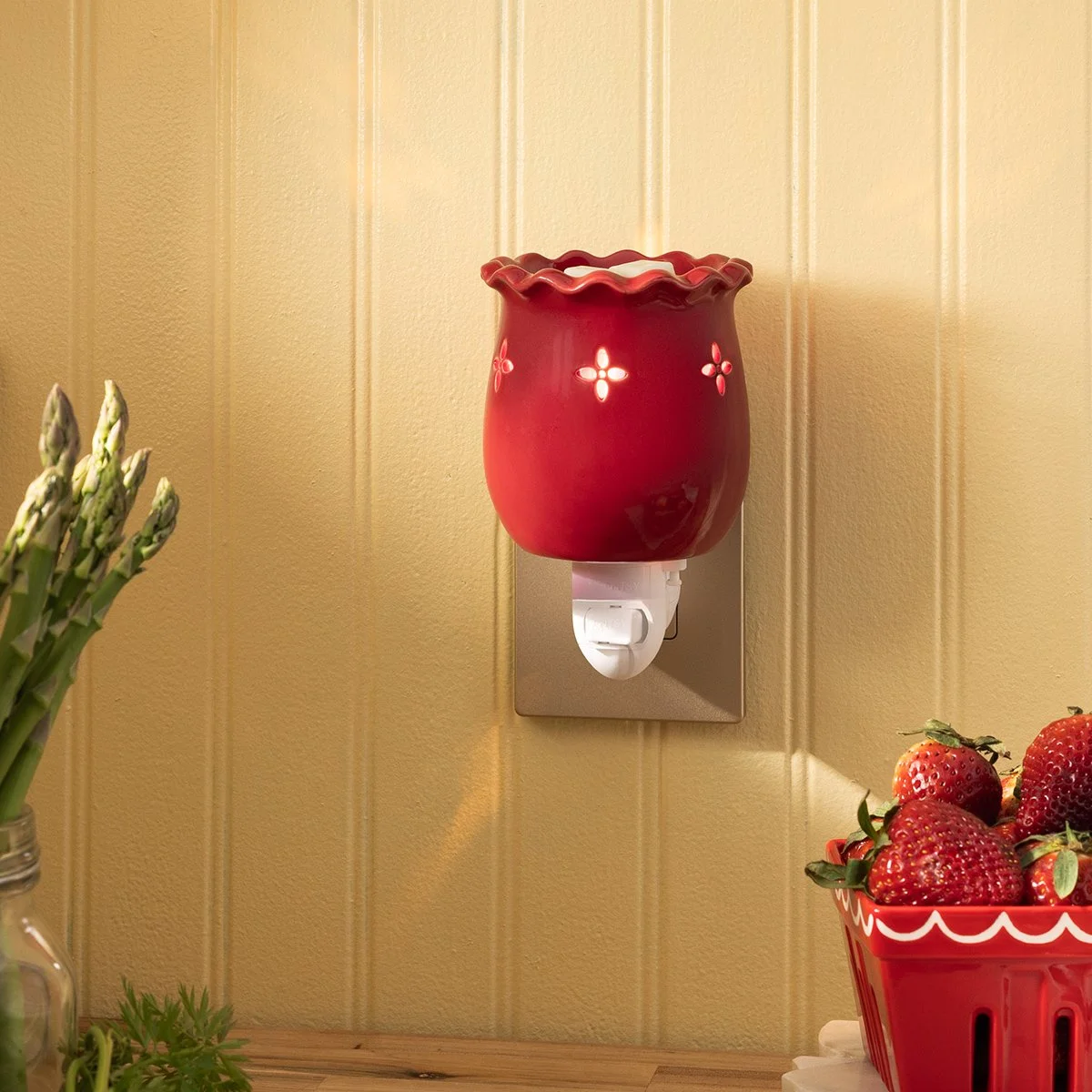 Laurel Red Mini Scentsy Warmer plugged into a wall outlet, glowing warmly beside fresh strawberries in a bright farmhouse kitchen scene.
