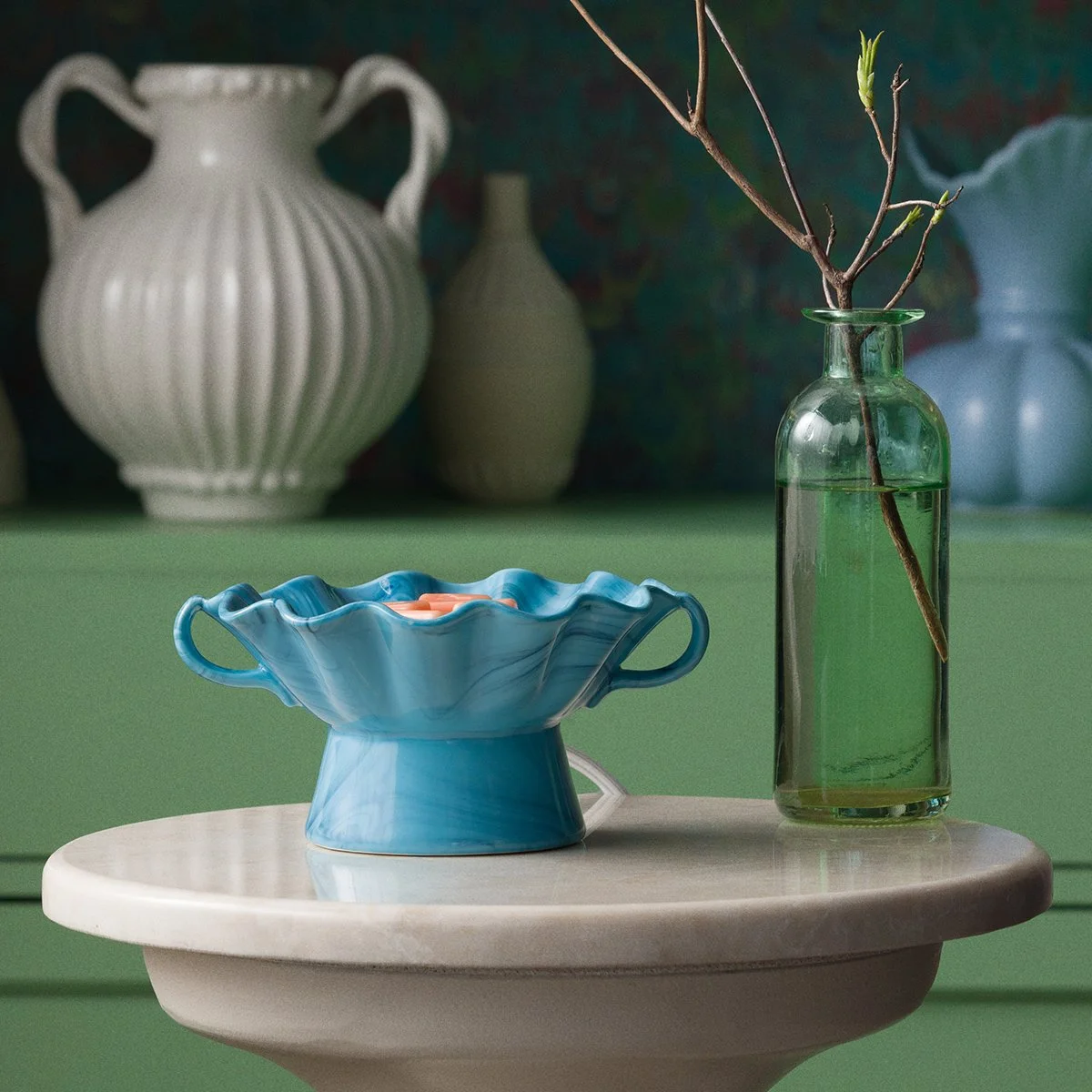 Blue Rialto Scentsy Warmer with flowing blue glass-inspired design displayed on a side table, exclusive to the July 2026 Italian Summer Monthly Edit