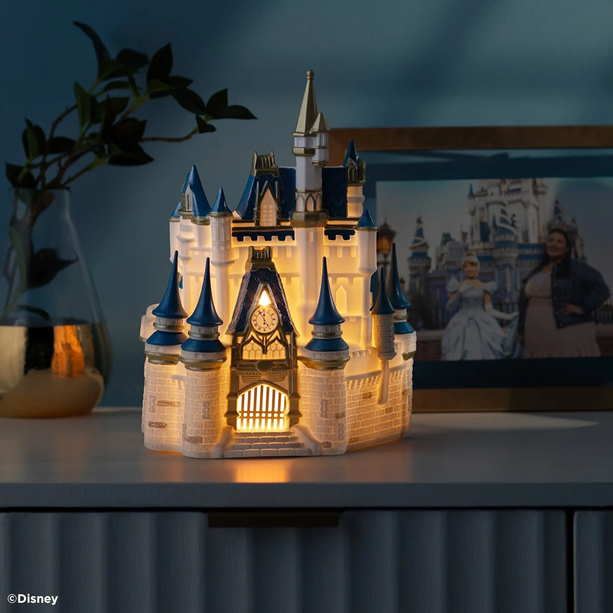 Disney Cinderella Castle Scentsy Warmer illuminated in a dim room highlighting the glowing castle windows and clock tower