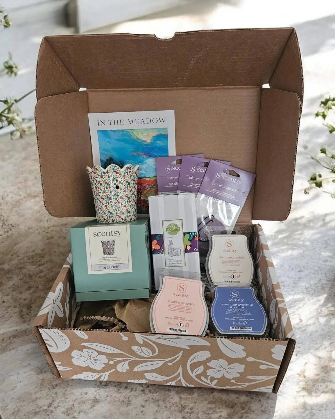 The June 2026 Scentsy Whiff Box opened to reveal the month's exclusive products, including the Floral Fields Mini Warmer, three Luna Scent Circles, and three Scentsy Wax Bars: Dancing Magnolias, Petals & Peaches, and Blooming Hyacinth & Santal. The c