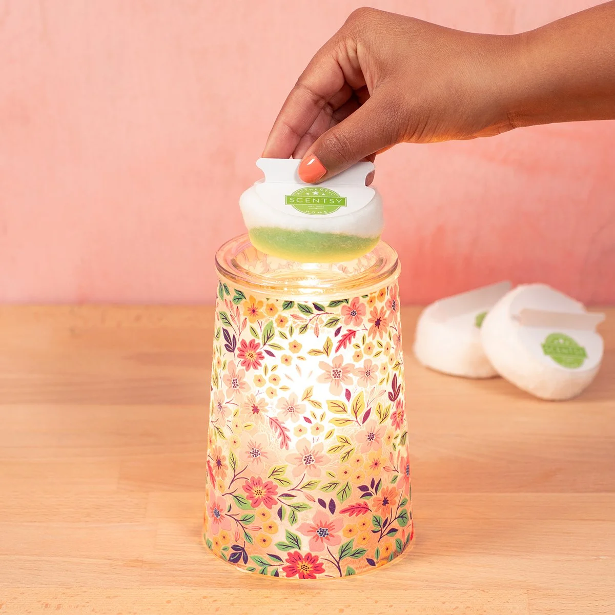 Wildflower Scentsy Warmer styled in a bright room glowing and using a cotton clean up