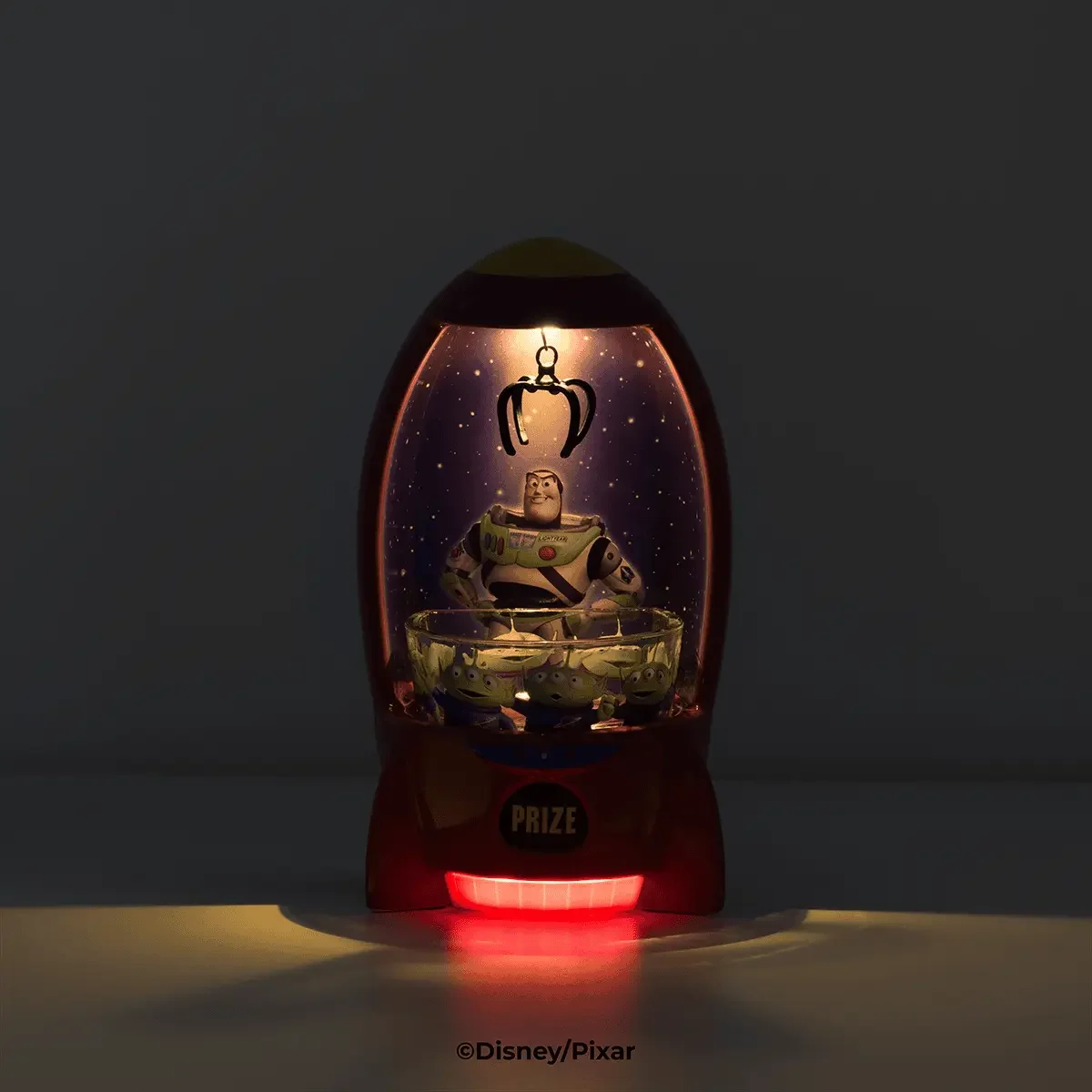 Disney Toy Story The Claw Scentsy Warmer glowing in the dark with claw and Buzz Lightyear illuminated
