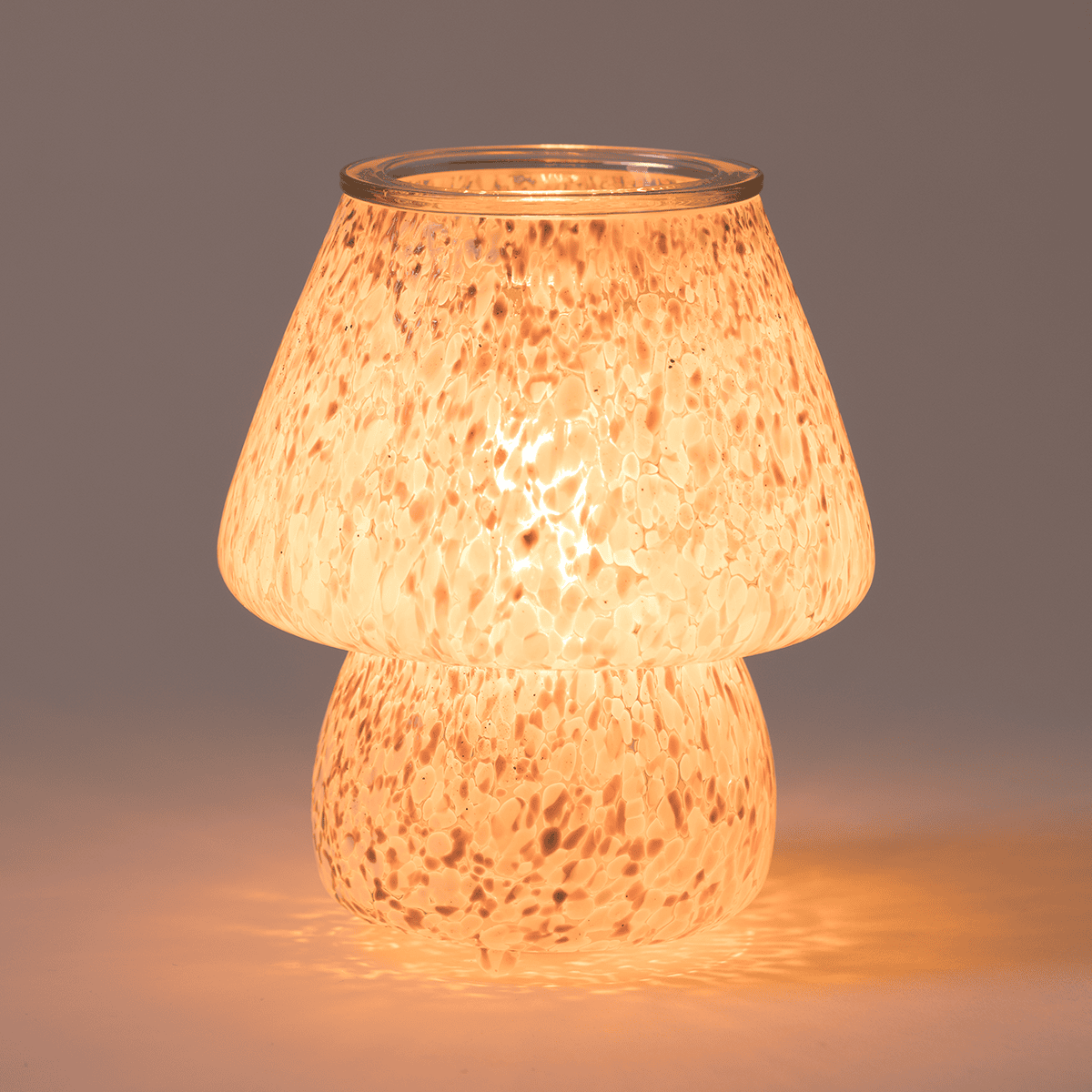 Confetti Glow Taupe Scentsy Warmer glowing warmly in a dark room, highlighting the mushroom shape and speckled glass