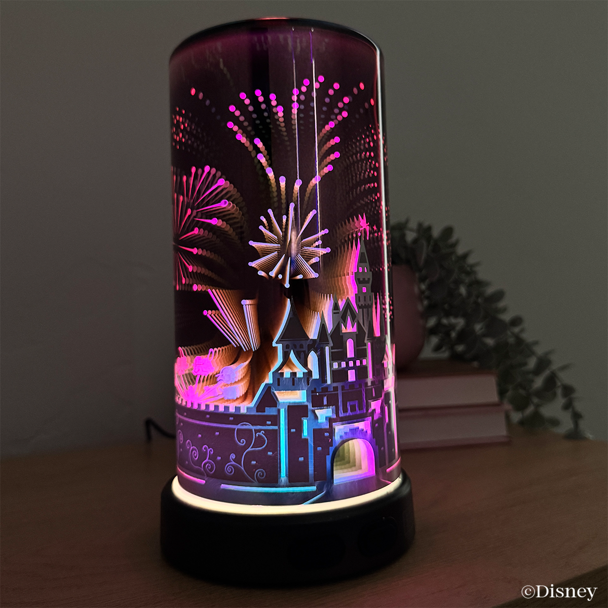The Sleeping Beauty Castle Scentsy Diffuser glowing in warm amber tones, highlighting the castle silhouette and fireworks design in a soft, ambient setting.