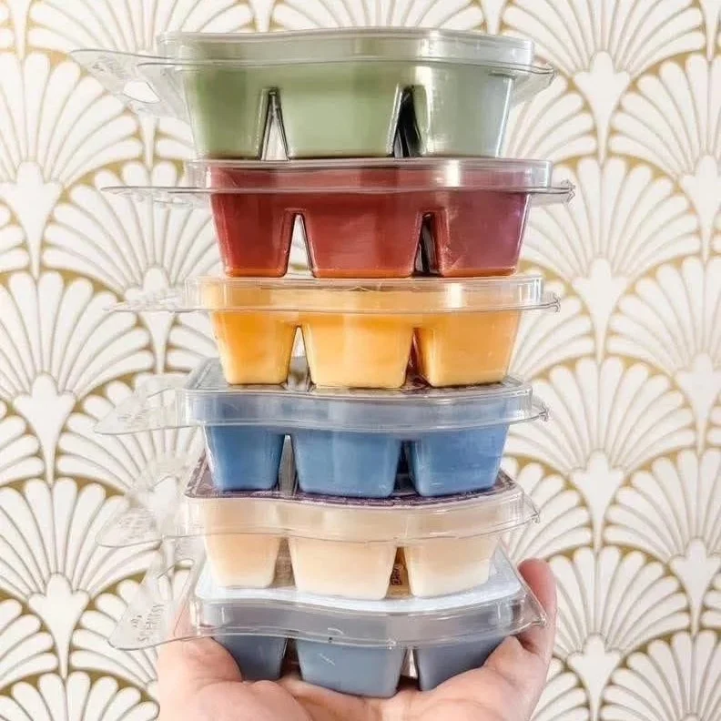 six scentsy wax bars stacked on top of each other styled in front of boutique wall paper