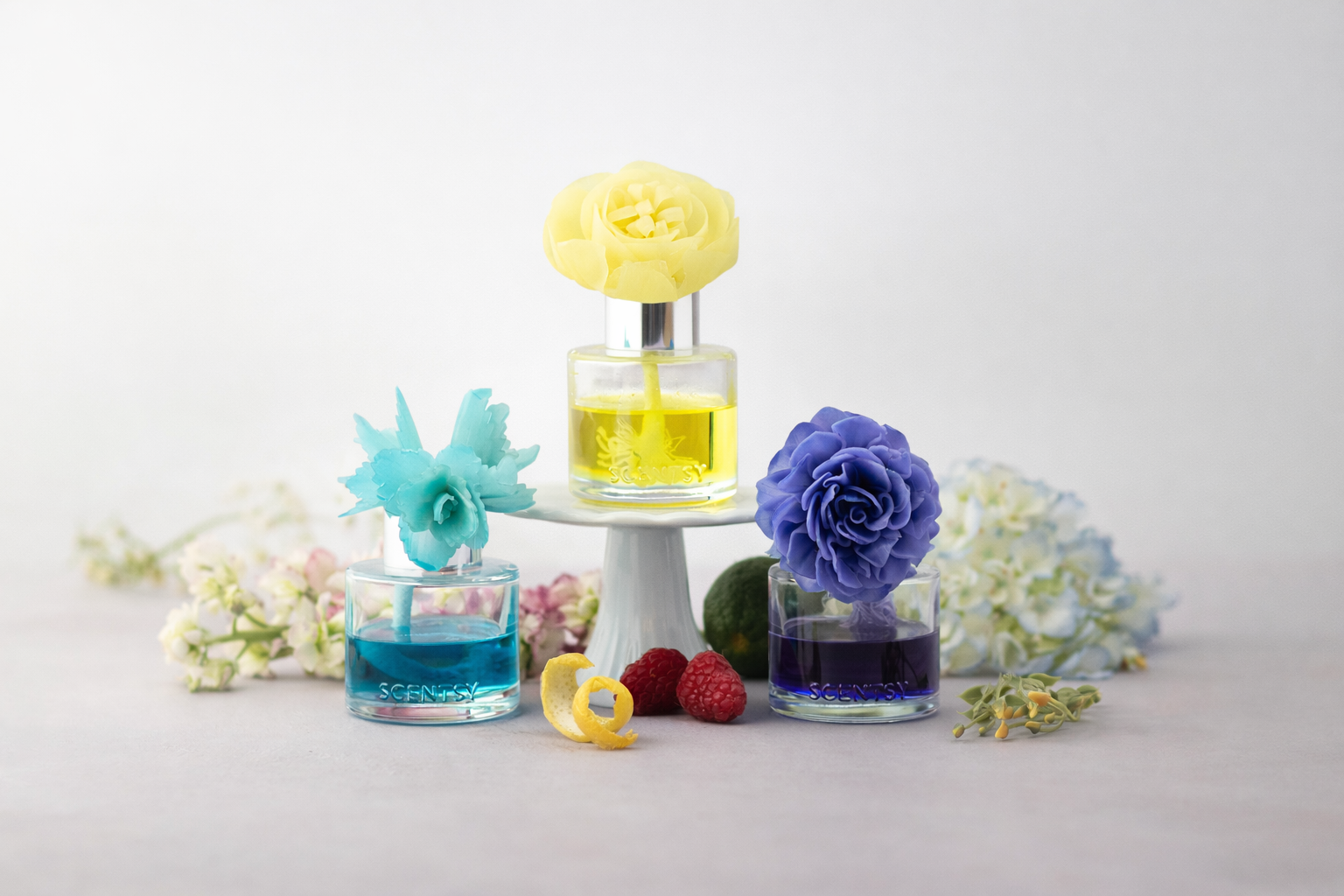 Scentsy Happiness Blooms Collection 2026 featuring three fragrance flowers in yellow, blue and purple oils styled against a soft neutral background