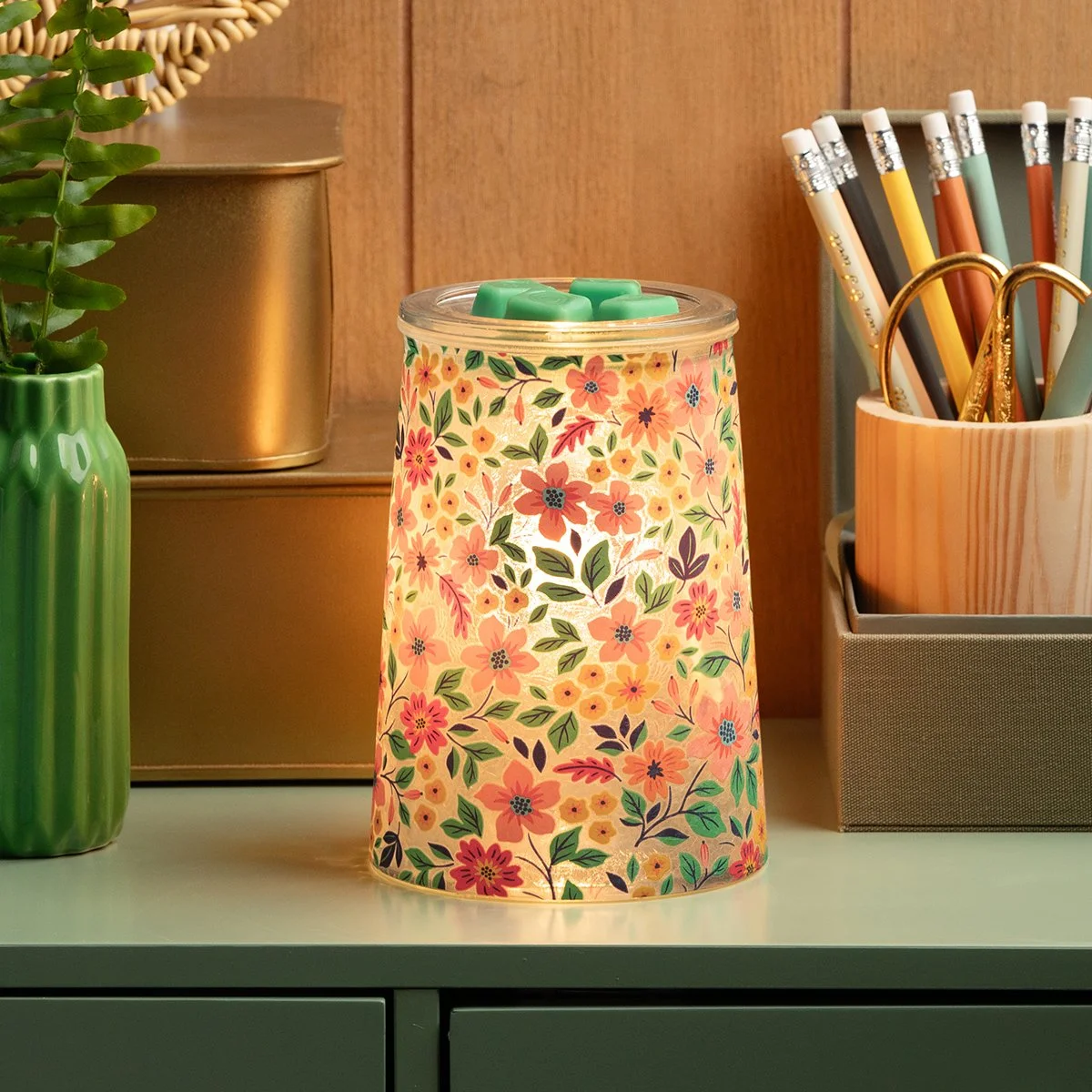 The Wildflower Scentsy Warmer features a playful floral pattern and soft illumination, styled with greenery and colorful accents to reflect the vibrant enliven decor style.