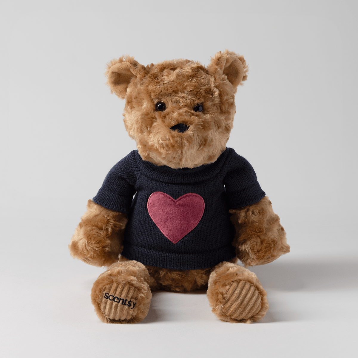 Banner the Bear Scentsy Buddy plush teddy bear wearing a navy sweater with a pink heart on a neutral background