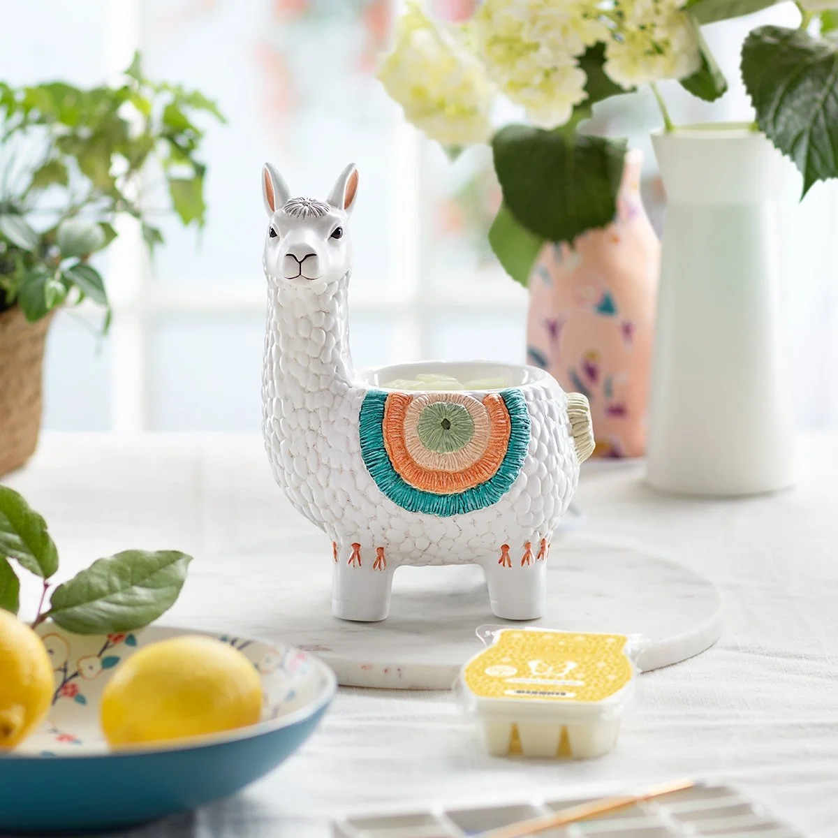 Llama Scentsy Warmer styled in a bright room glowing with wax in the dish