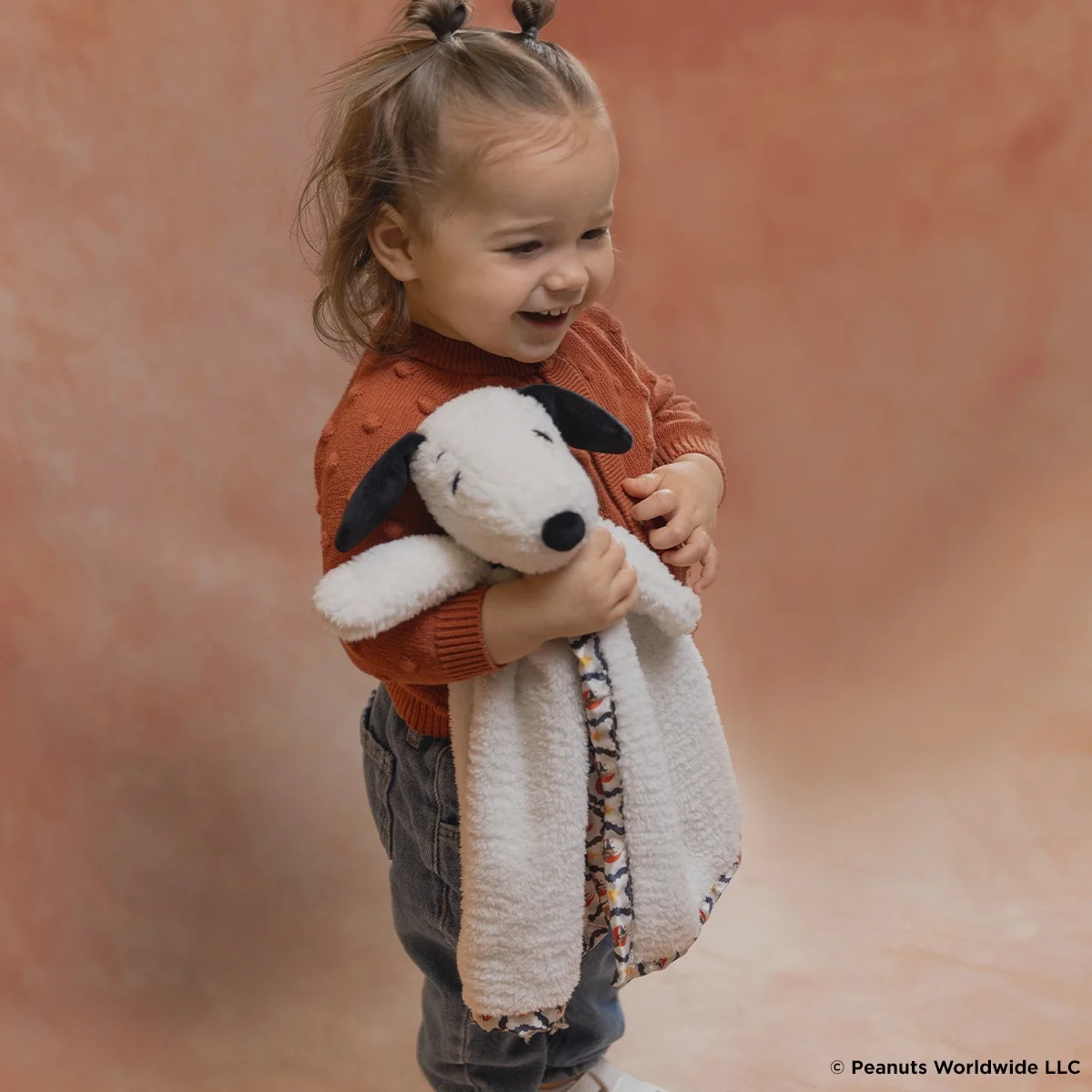 Young child cuddling the Snoopy Happy Halloween Scentsy Blankie Buddy with soft white plush and Halloween-patterned fabric.