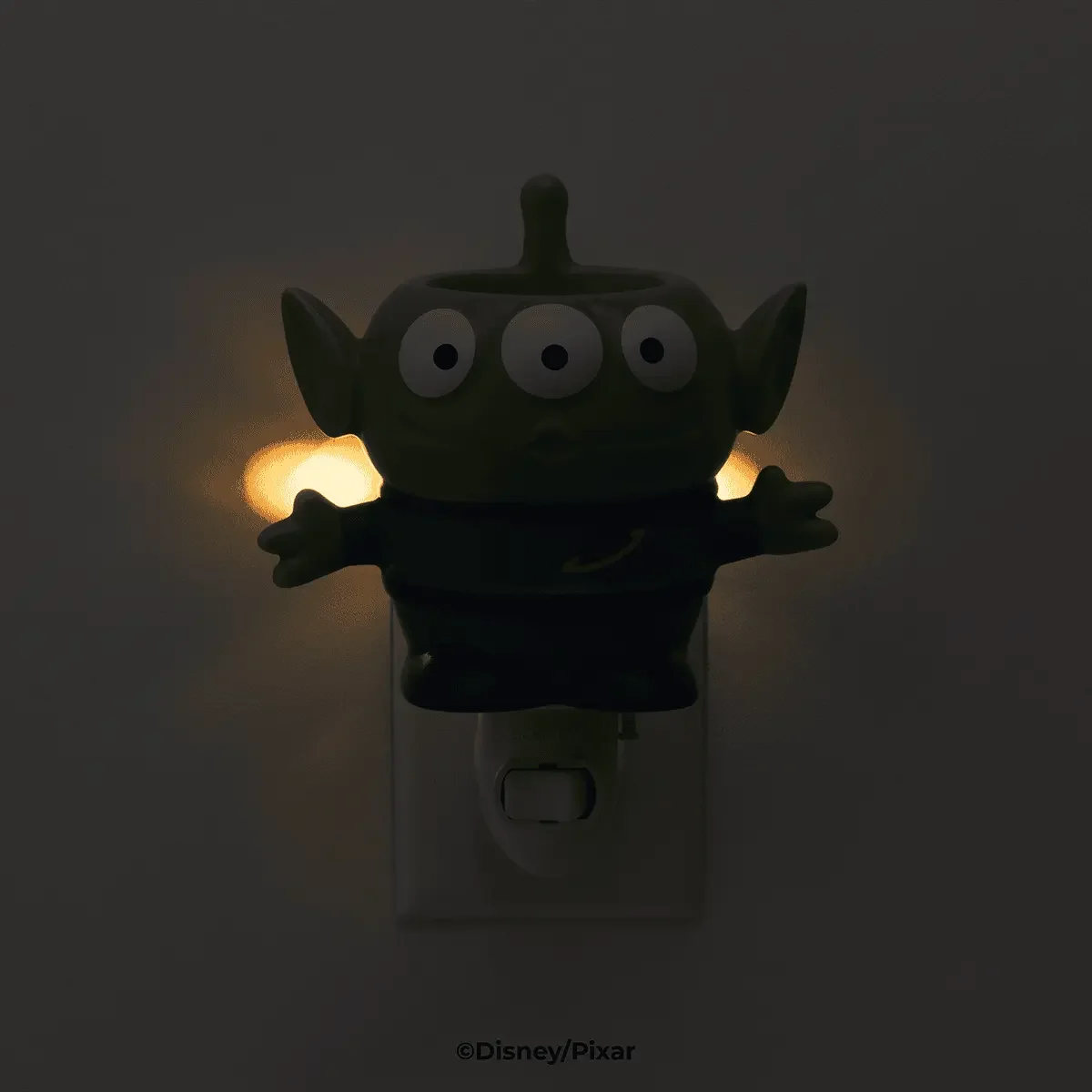 Toy Story Alien Scentsy Mini Warmer glowing on wall outlet with soft light