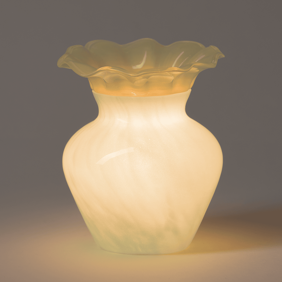 Seafoam Bloom Scentsy Warmer glowing warmly in a dim room, highlighting its soft seafoam glass and floral silhouette