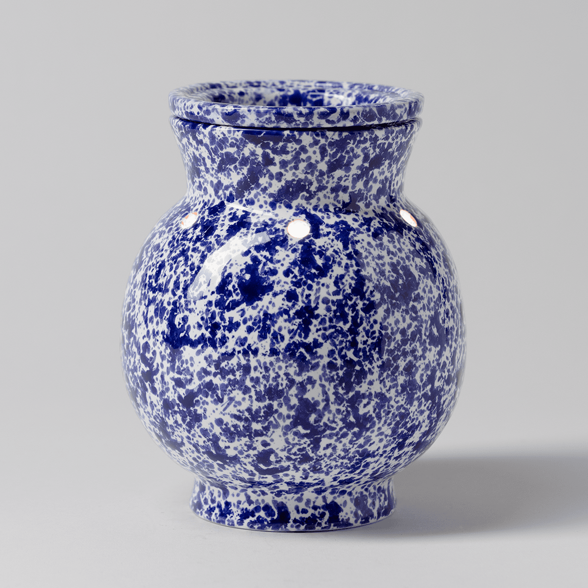 Blue Spongeware Scentsy warmer illuminated with light visible through small neck cutouts