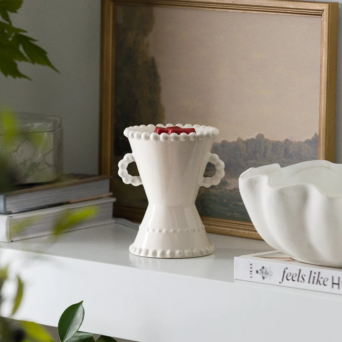 White Scentsy Belaire warmer styled on a shelf with framed artwork and décor