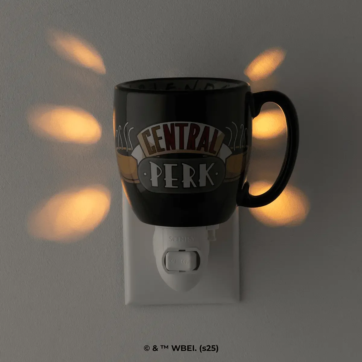 Friends Central Perk mini Scentsy warmer glowing on wall outlet with warm light pattern