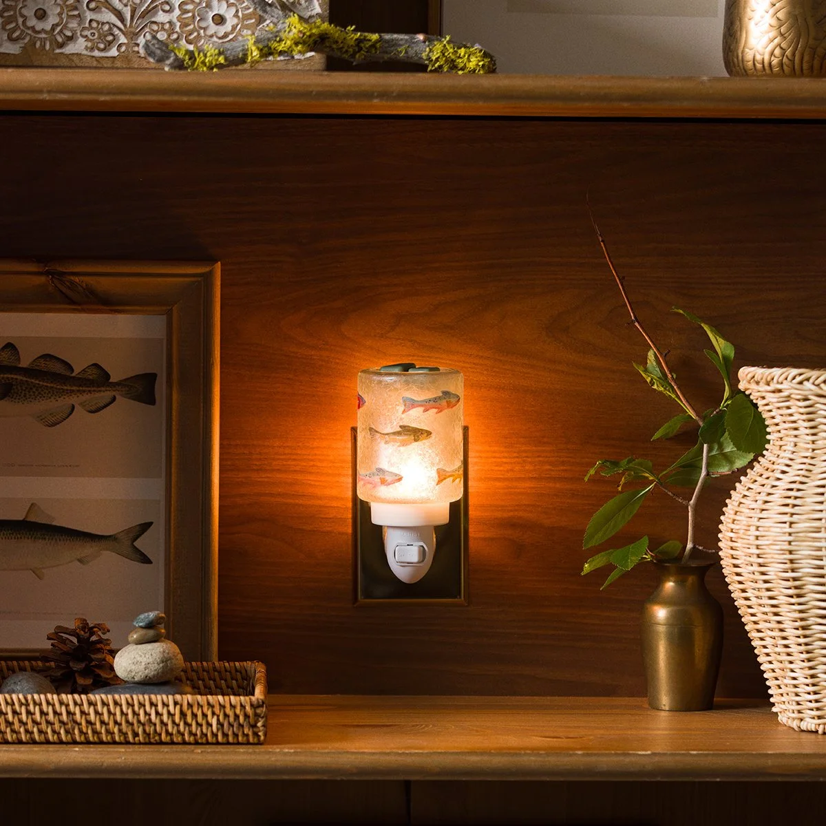 Scentsy Silverfin Mini Warmer glowing against warm wood décor with framed fish artwork