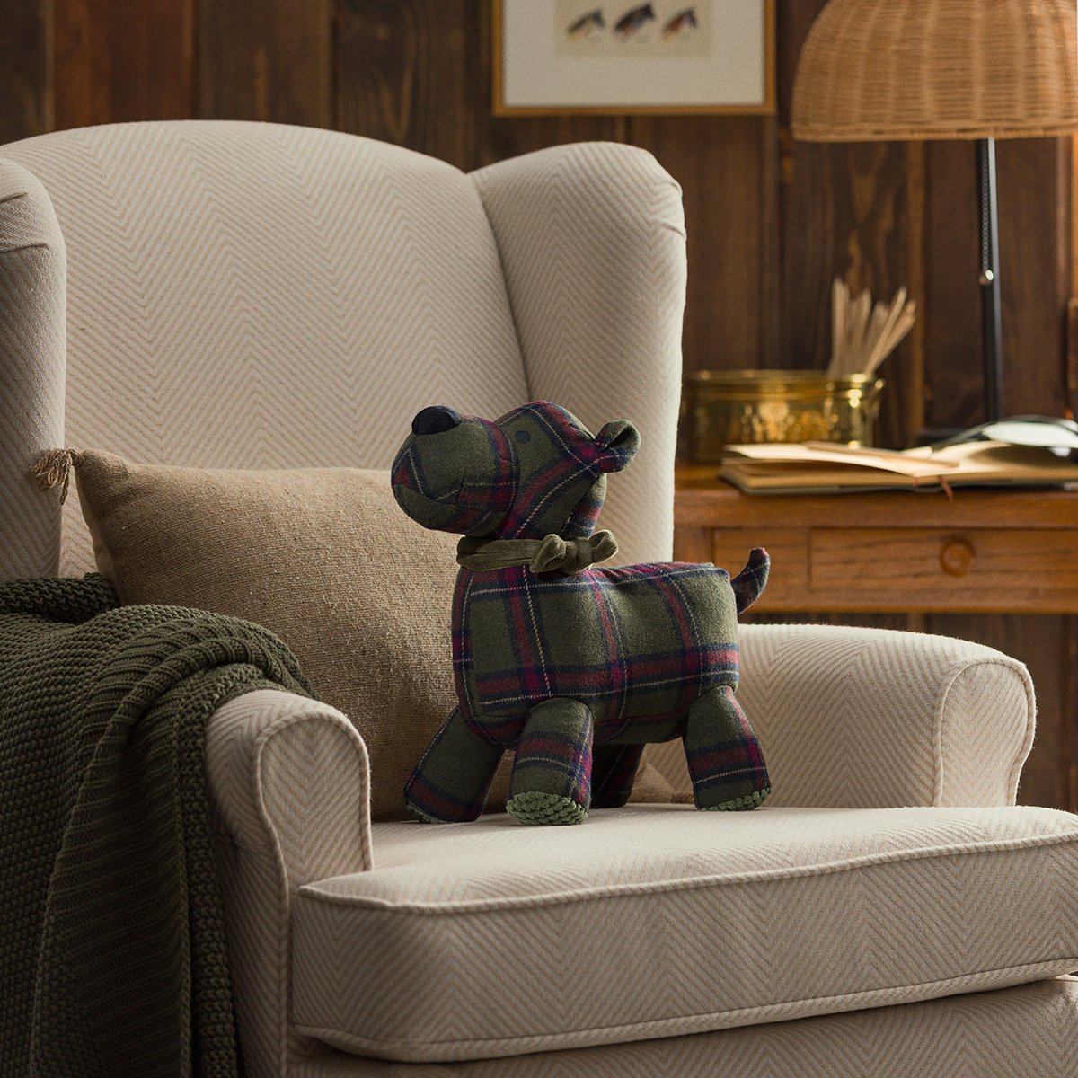 Sutton the Scottie Dog Scentsy Buddy in green plaid displayed on a cozy armchair in a cabin setting