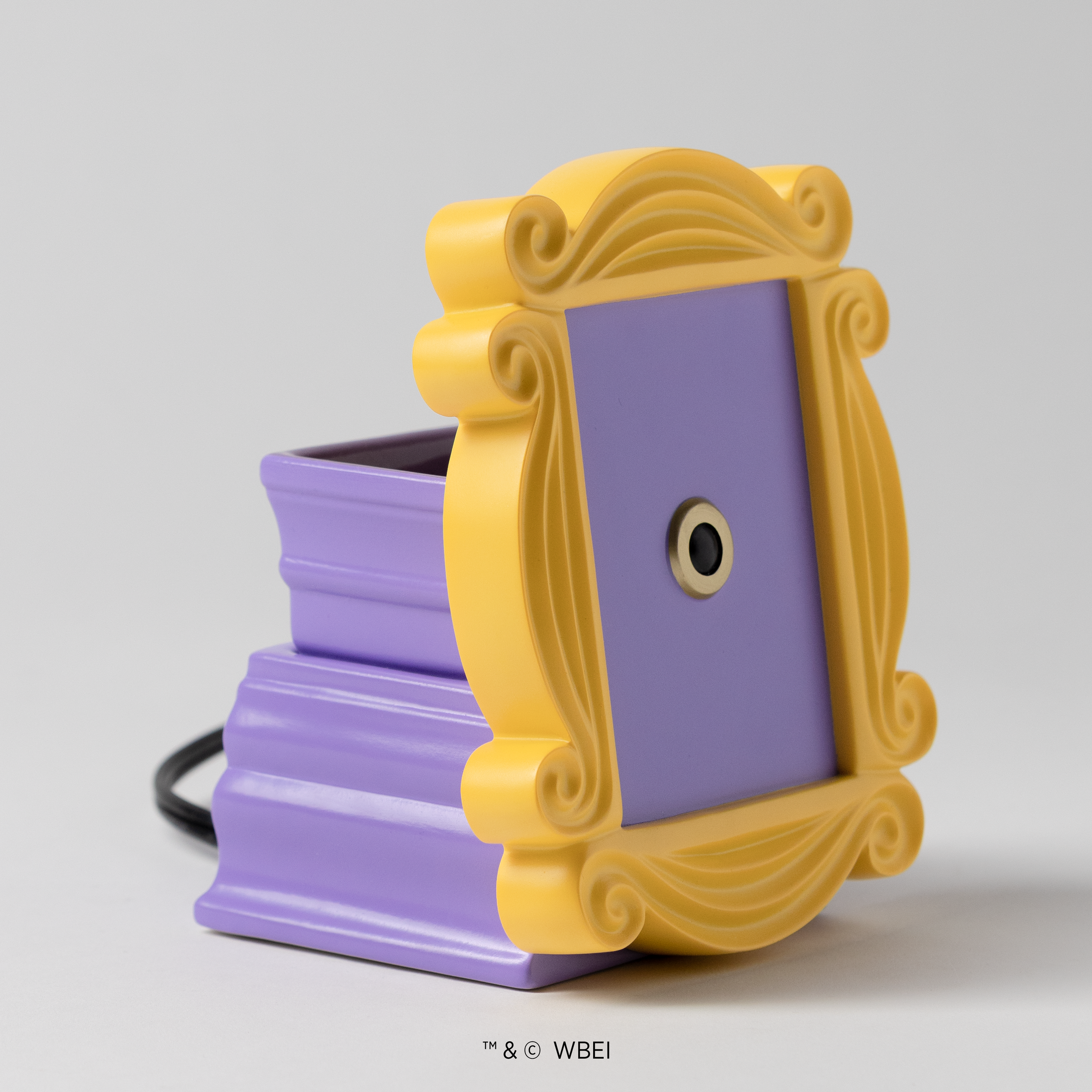 Angled view of the Friends The One With the Yellow Frame Scentsy Warmer showing the yellow frame detail and lavender wax dish base.