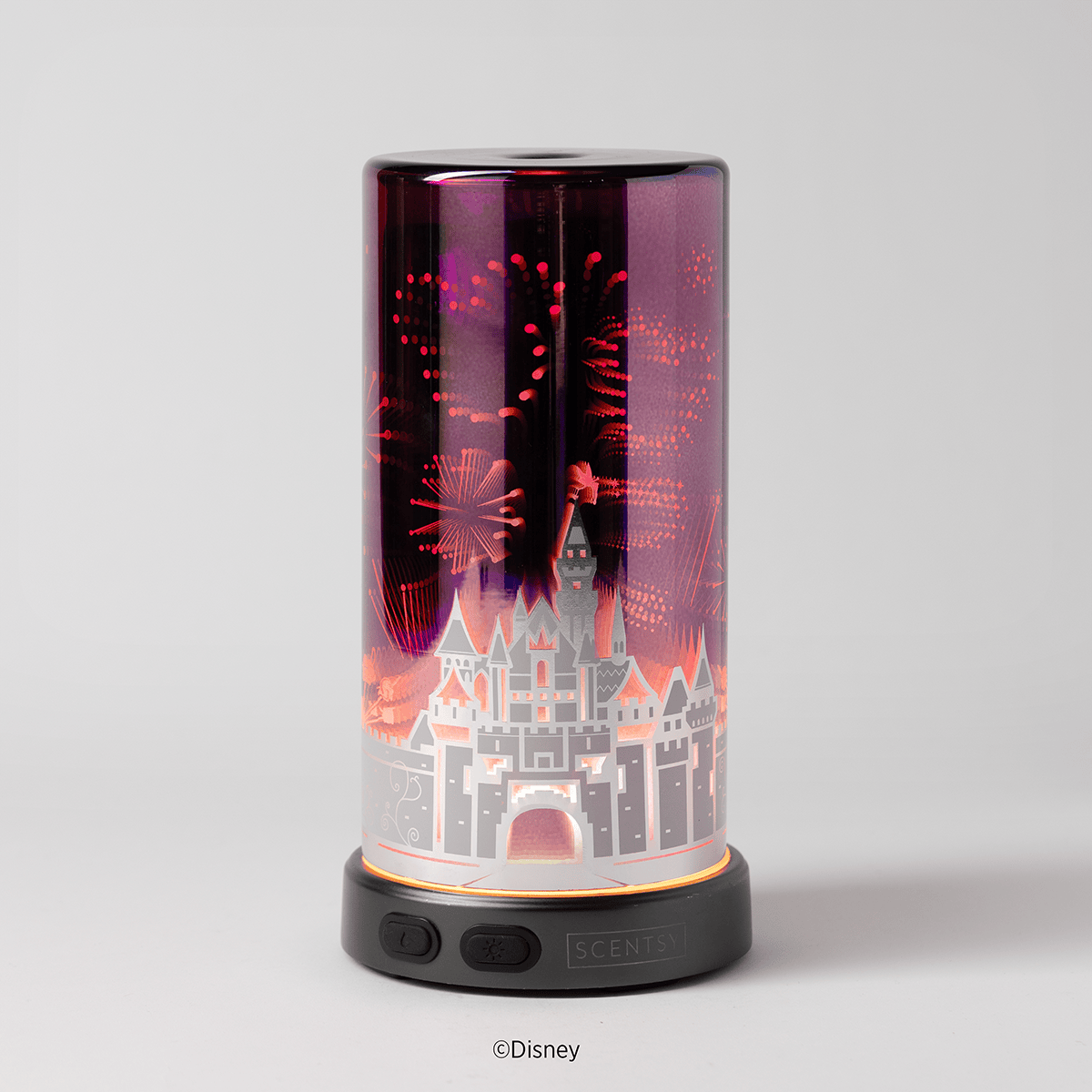 The Sleeping Beauty Castle Scentsy Diffuser glowing in warm amber tones, highlighting the castle silhouette and fireworks design in a soft, ambient setting.
