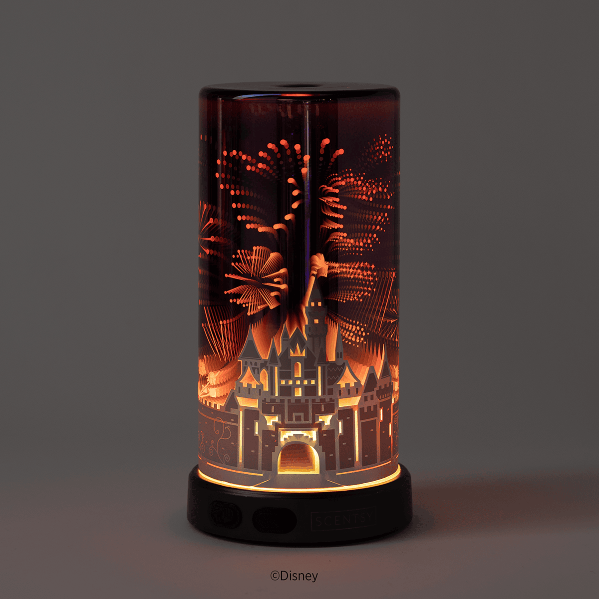 The Sleeping Beauty Castle Scentsy Diffuser shown in a dark setting with illuminated fireworks details glowing, emphasizing the diffuser’s light effects.