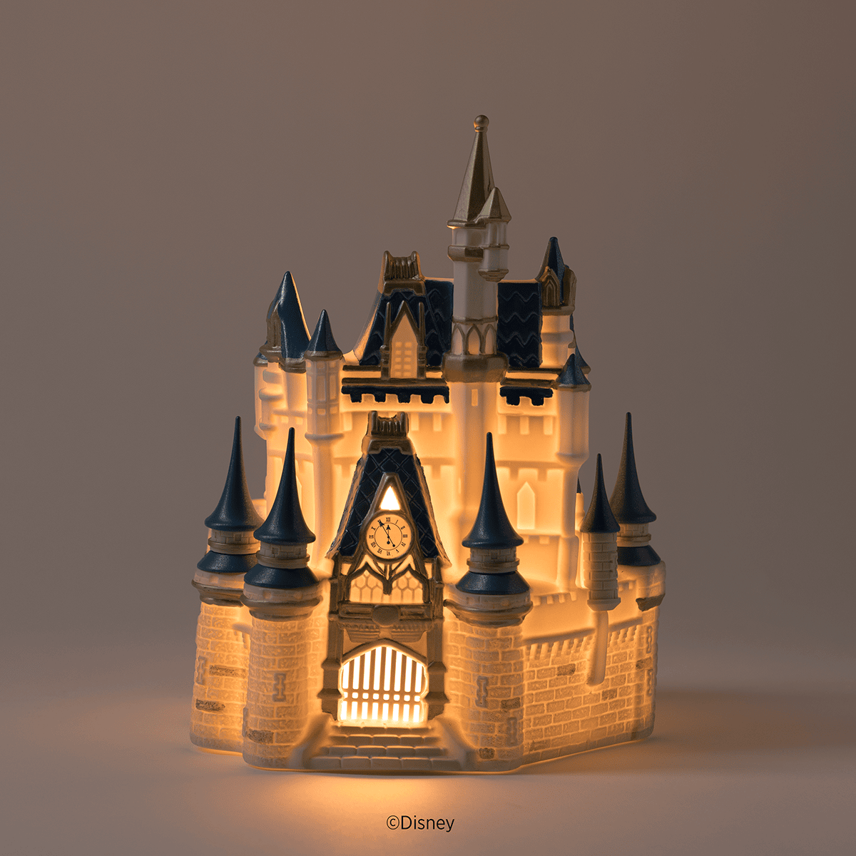 Disney Cinderella Castle Scentsy Warmer illuminated with warm light highlighting the castle clock tower and windows