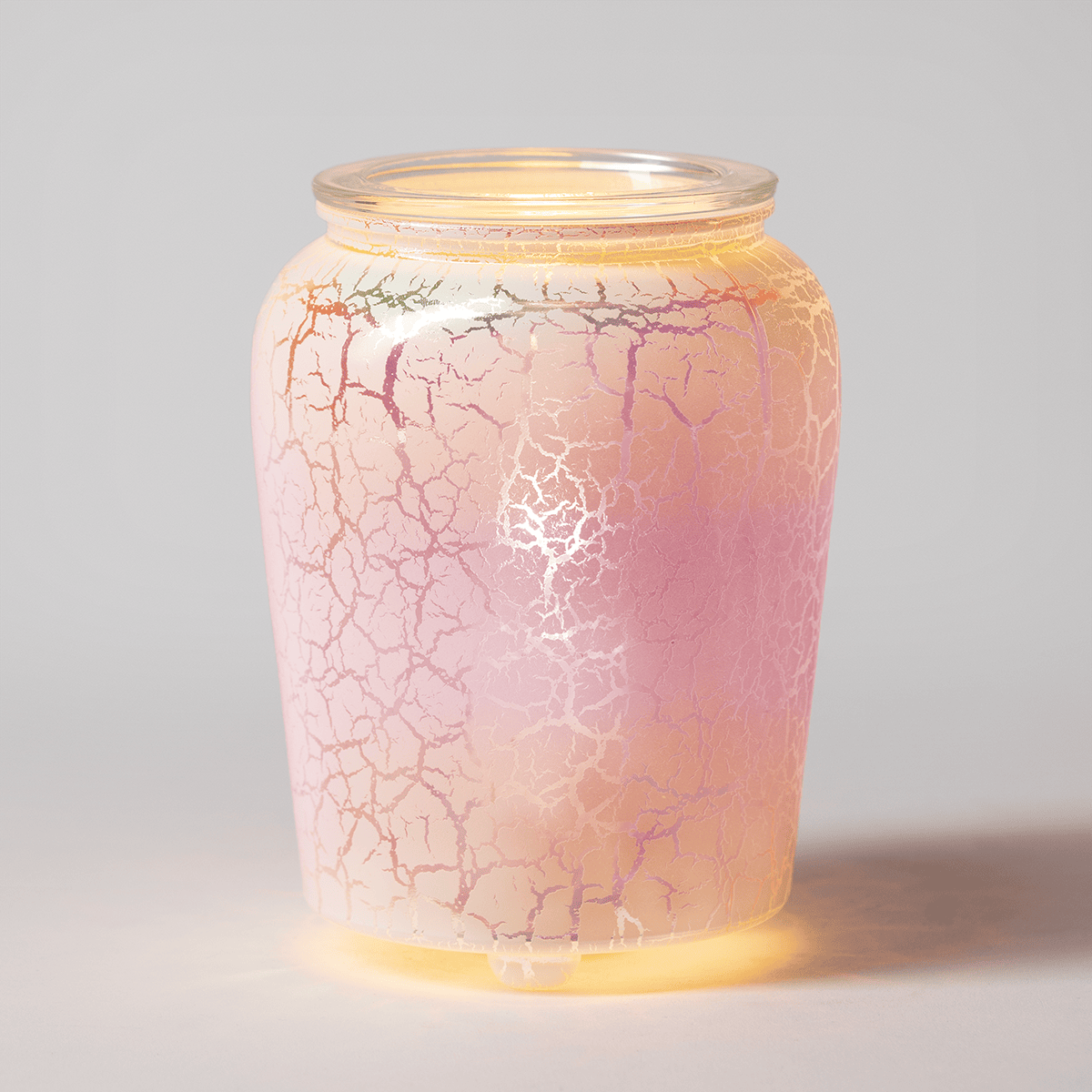 The Iridescent Rainbow Warmer turned on, casting a warm golden glow with soft rainbow hues shining through the crackled glass