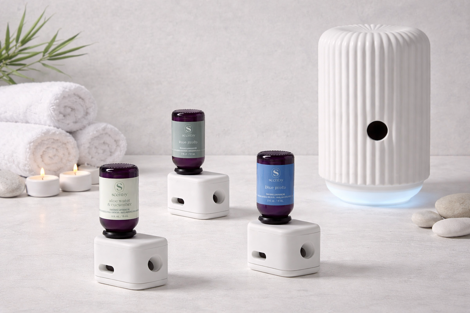 Three Scentsy fragrance cartridges displayed individually next to the white Solo smart diffuser, styled in a calm spa-inspired setting with neutral tones, towels, stones, and soft lighting.