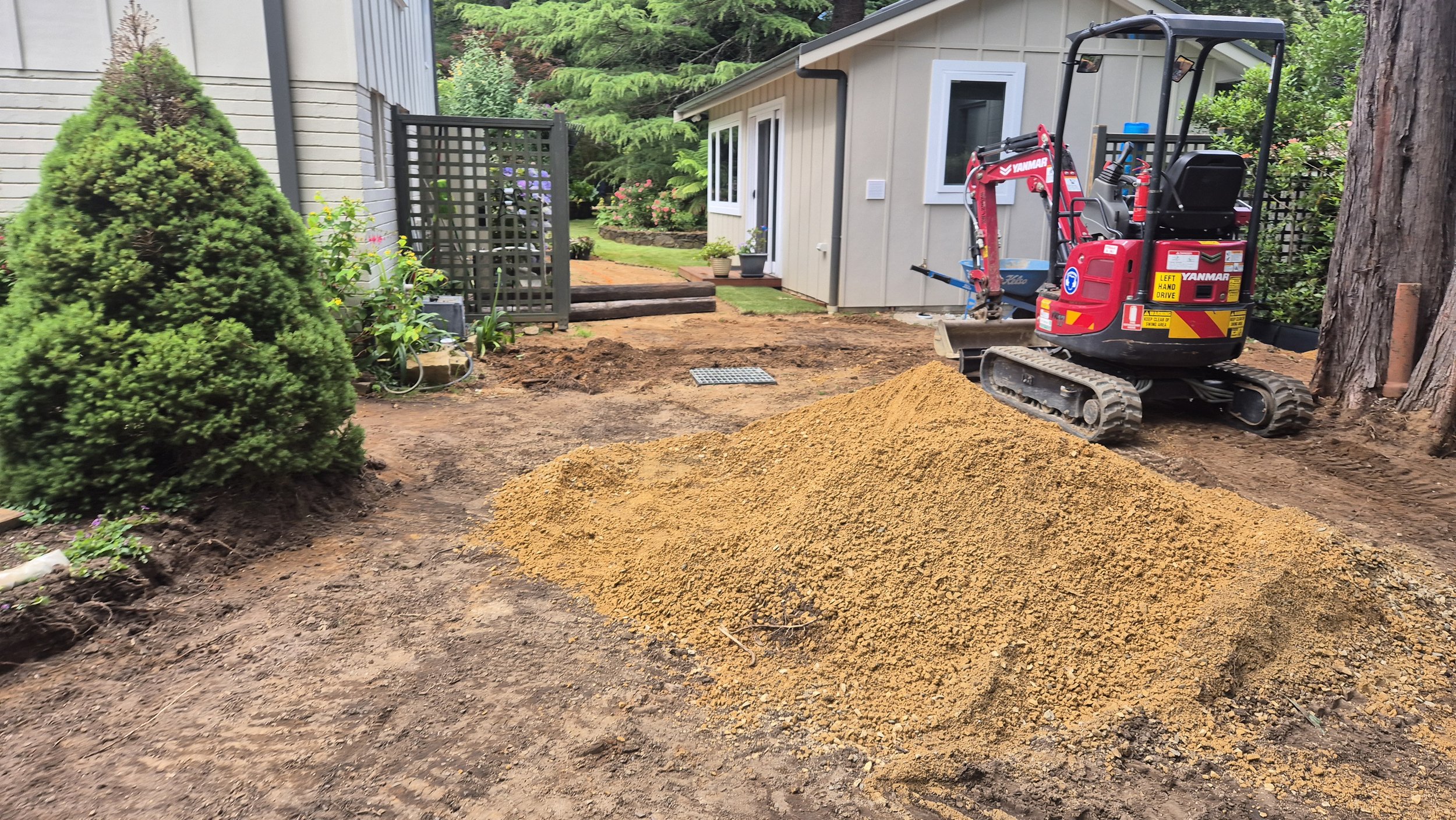 Small excavator and pile of dirt in residential backyard under construction