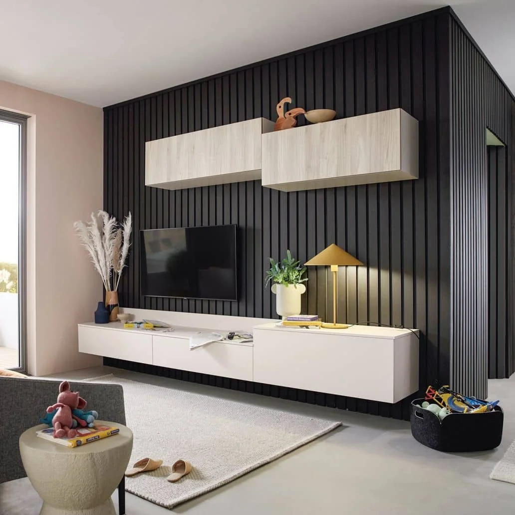 Modern living room with black paneled accent wall, white floating TV console, a flat-screen TV, decorative items, and toys.