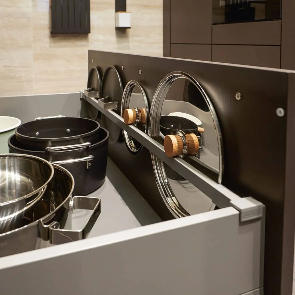 Kitchen drawer with pot lid organizers containing pot lids and saucepans.