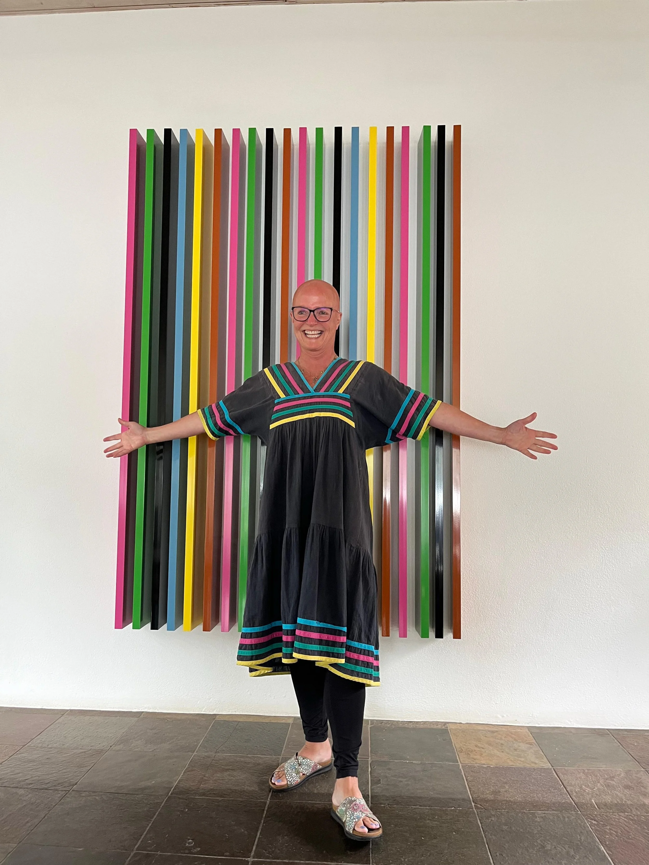 Jane wearing a multi coloured dress standing infront of an multi coloured installation