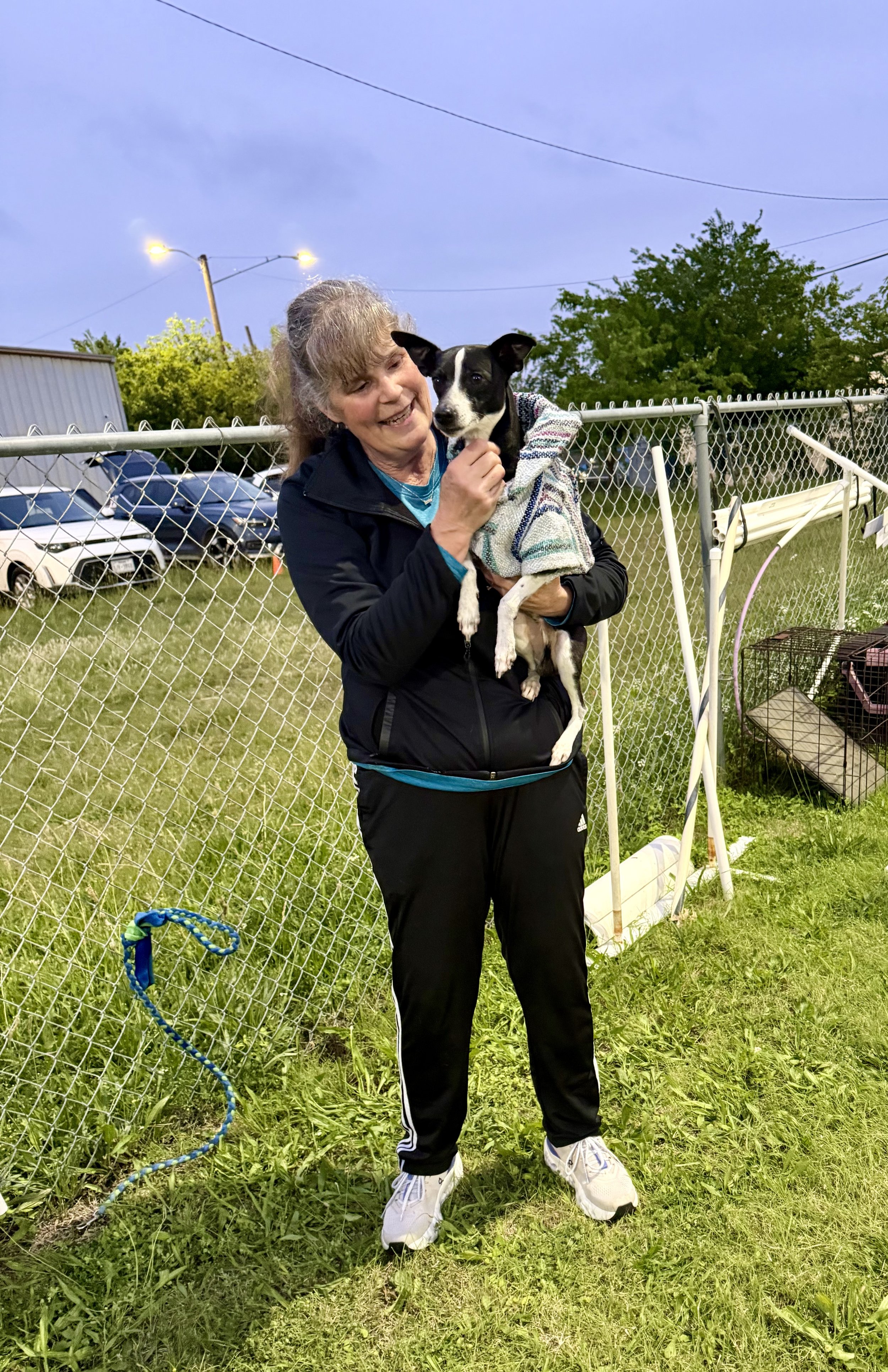 Handler holding dog wearing jacket