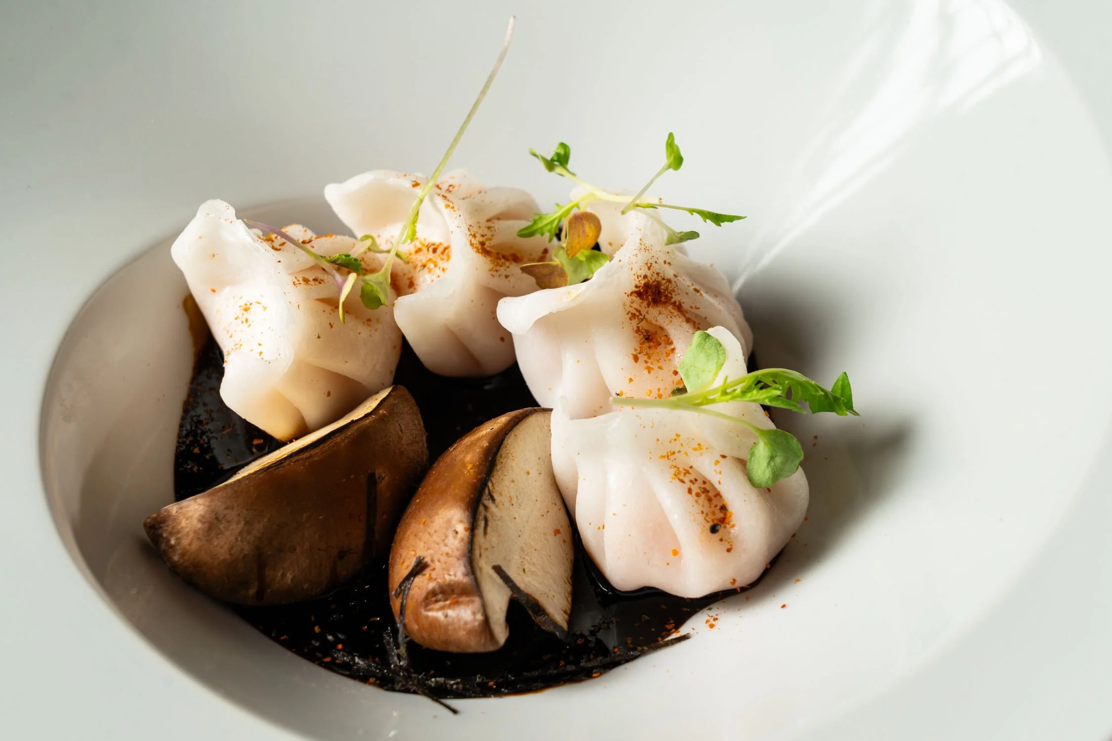 Plato con crema, hongos y microverdes en una fuente blanca.
