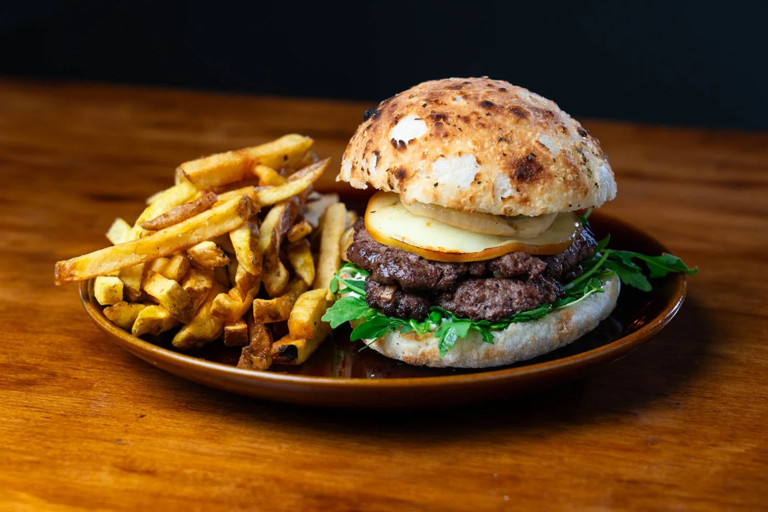 Hamburguesa con carne, queso, lechuga y pan, acompañada de papas fritas.