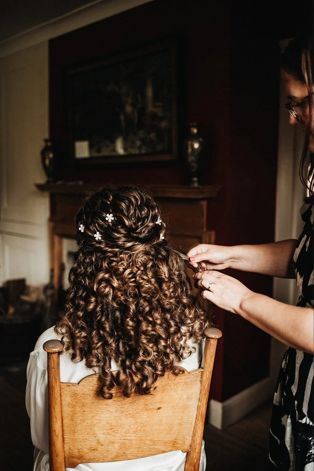 A bride having finishing touches made to her naturally curly bridal hairstyle ready for her wedding in Suffolk.
