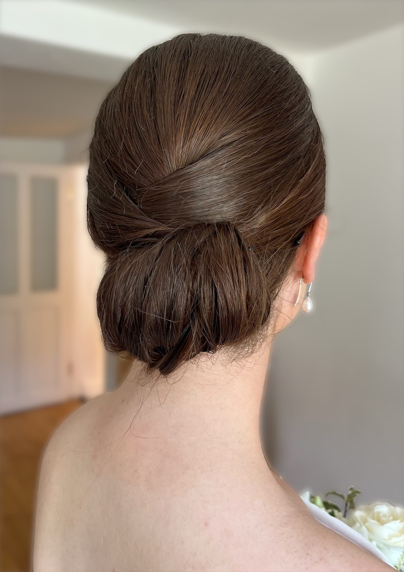 A clean bridal updo chignon hair style, created on dark hair.