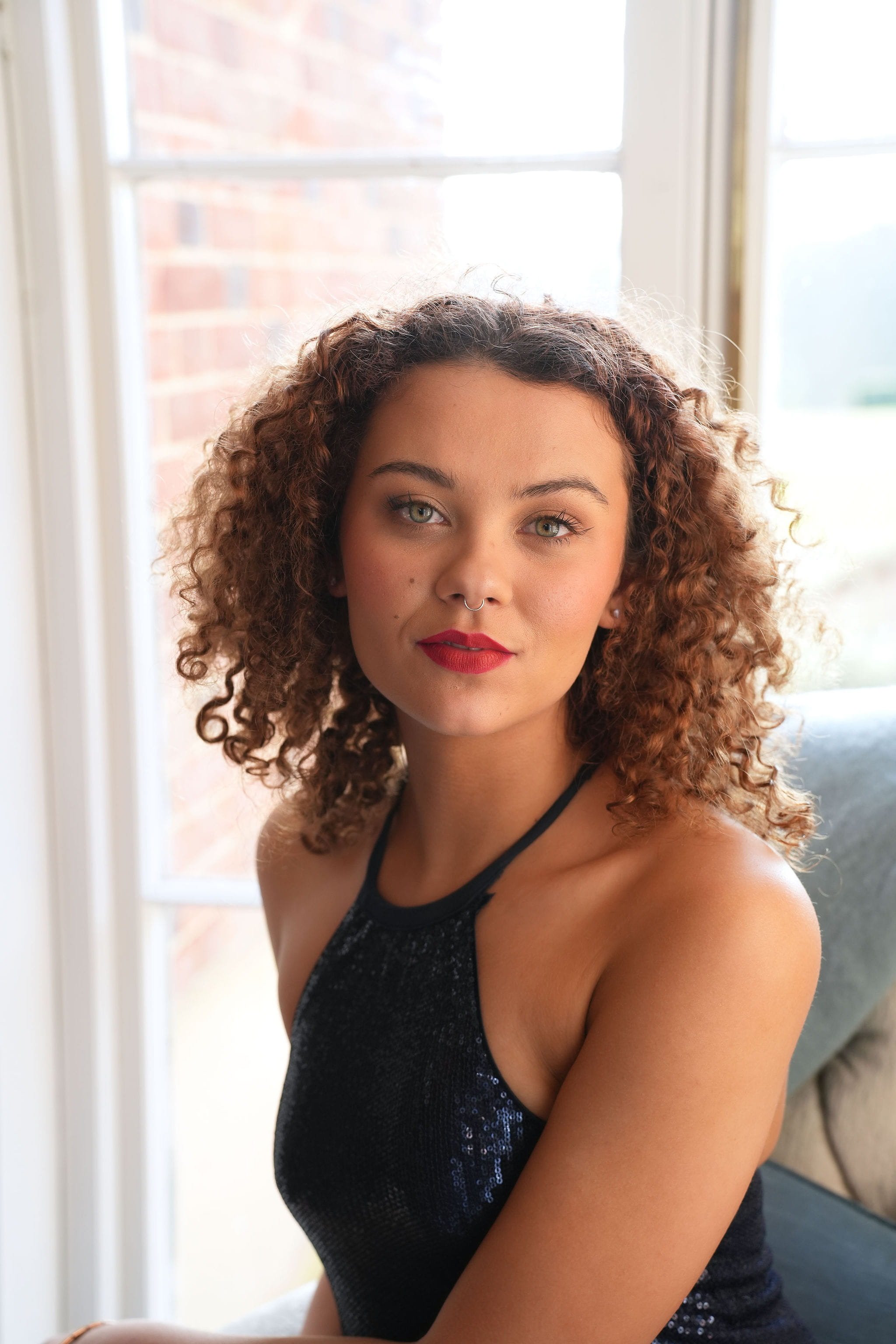 A portrait shot of a woman wearing a makeup look with natural skin and a red lip.