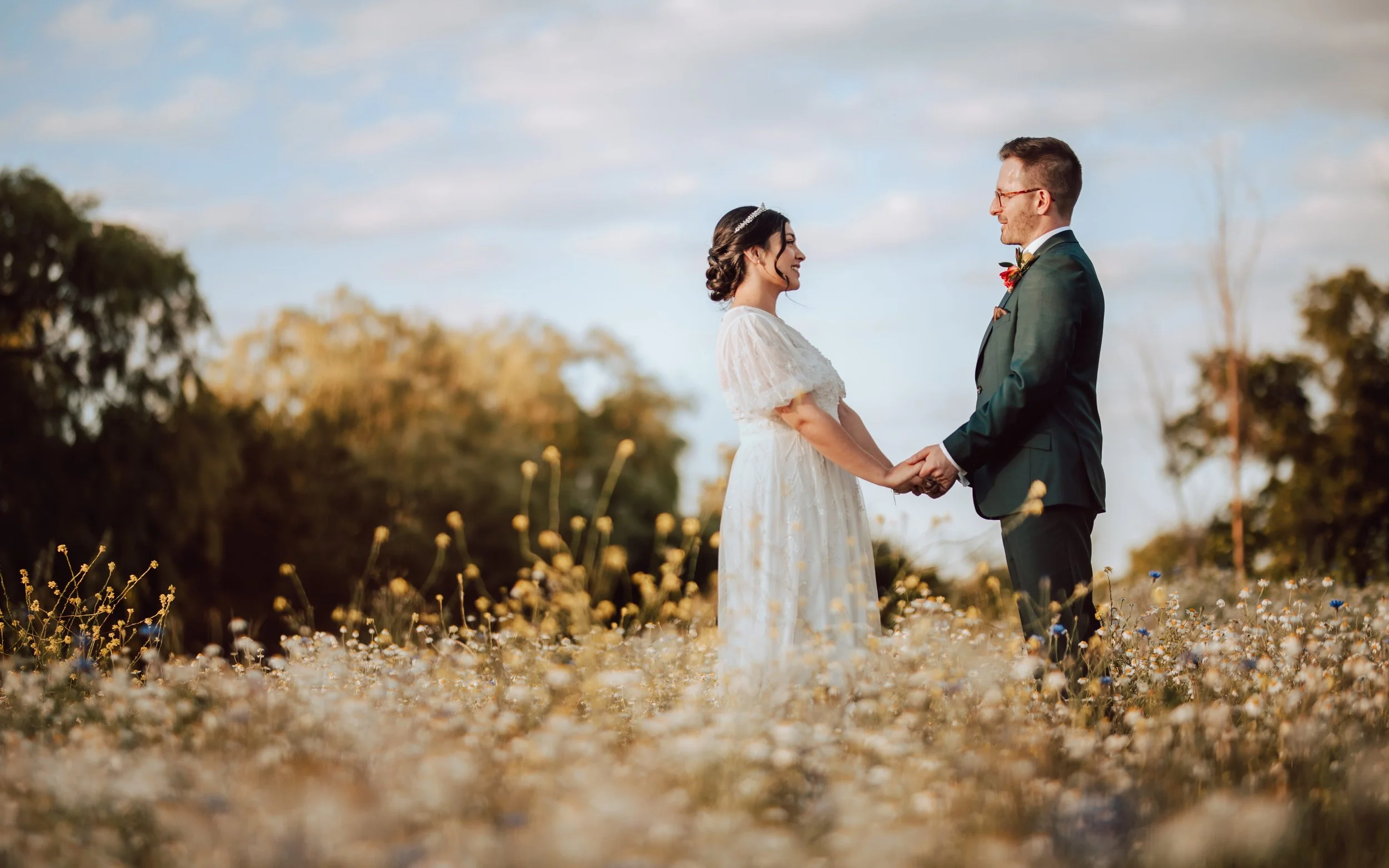 A couple holding hands in a field, following their wedding ceremony at Channels Estate in Chelmsford, Essex.