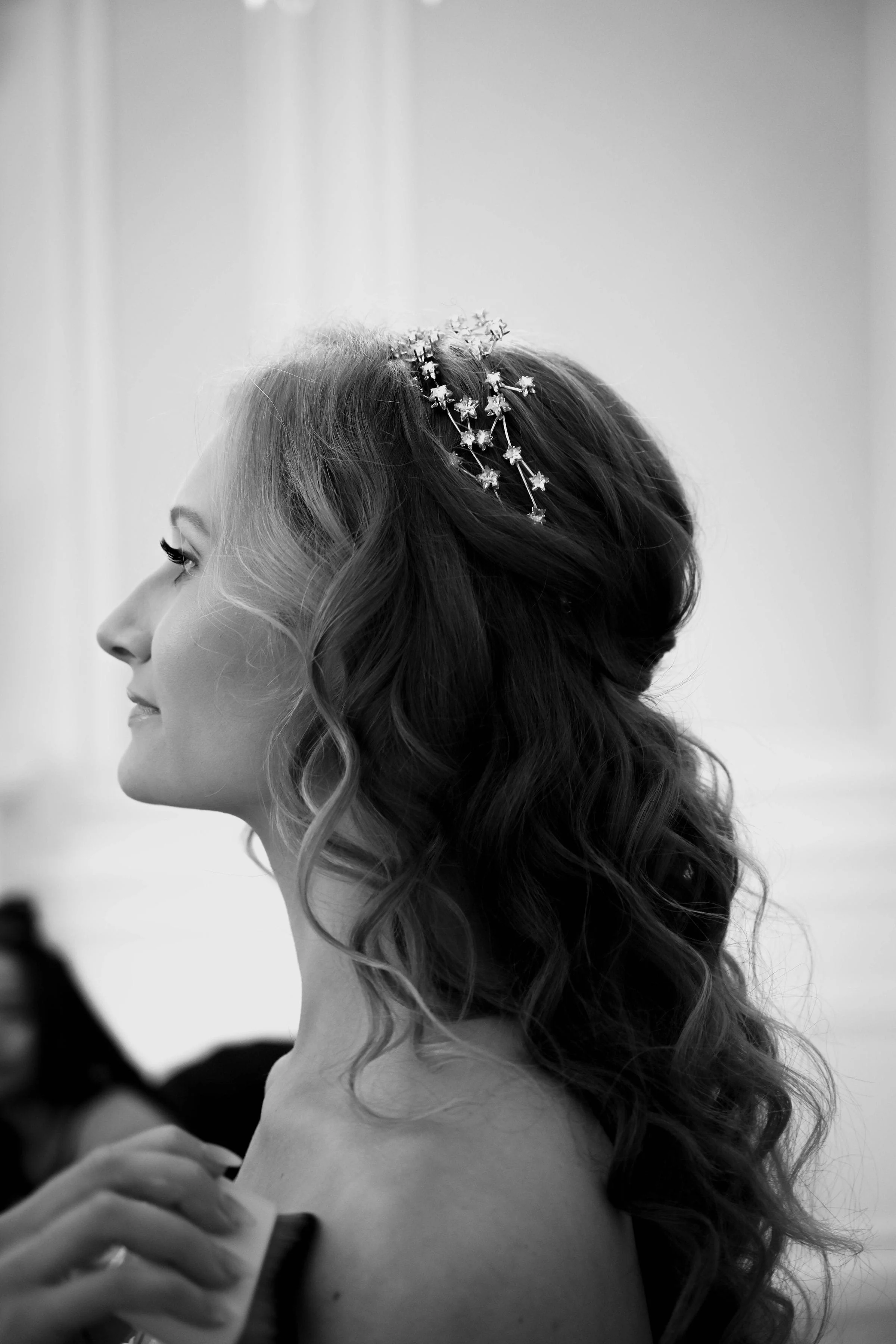 A profile view of a bride, wearing her hair in natural looking waves styled half up half down, ready for her wedding day in Essex.