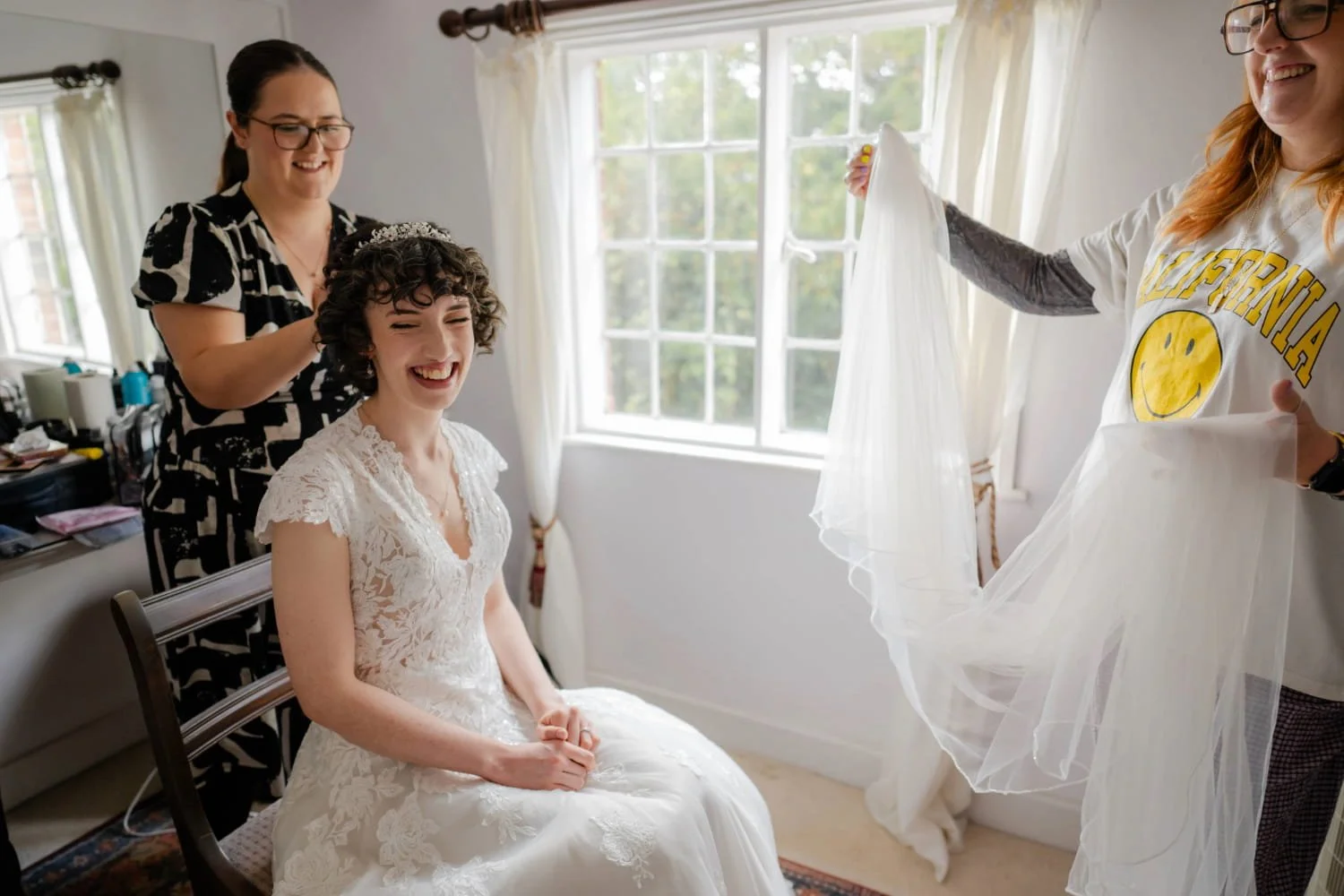 A bride having final touches made to her wedding hairstyle, before having her veil fitted at Hedingham Castle in Essex