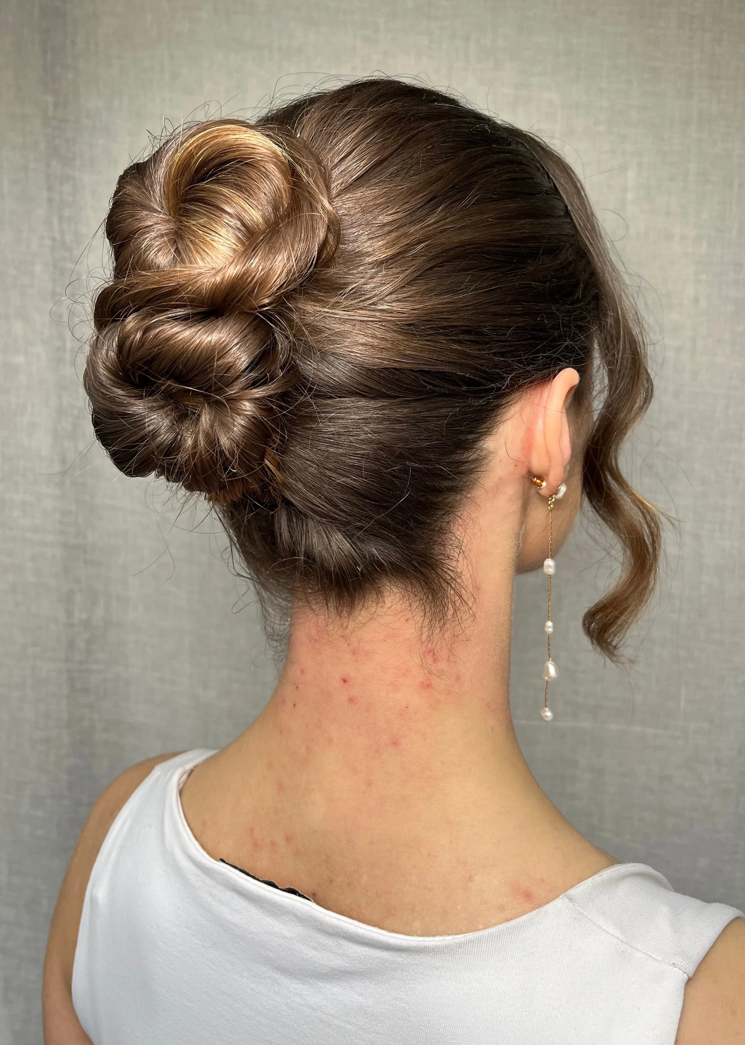 A mid height bridal updo idea styled into a figure of eight bun, on long mid brown hair.