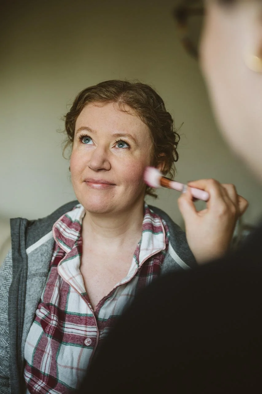 A bride having final touches made to her natural bridal makeup look, before her wedding ceremony at Leez Priory in Chelmsford.