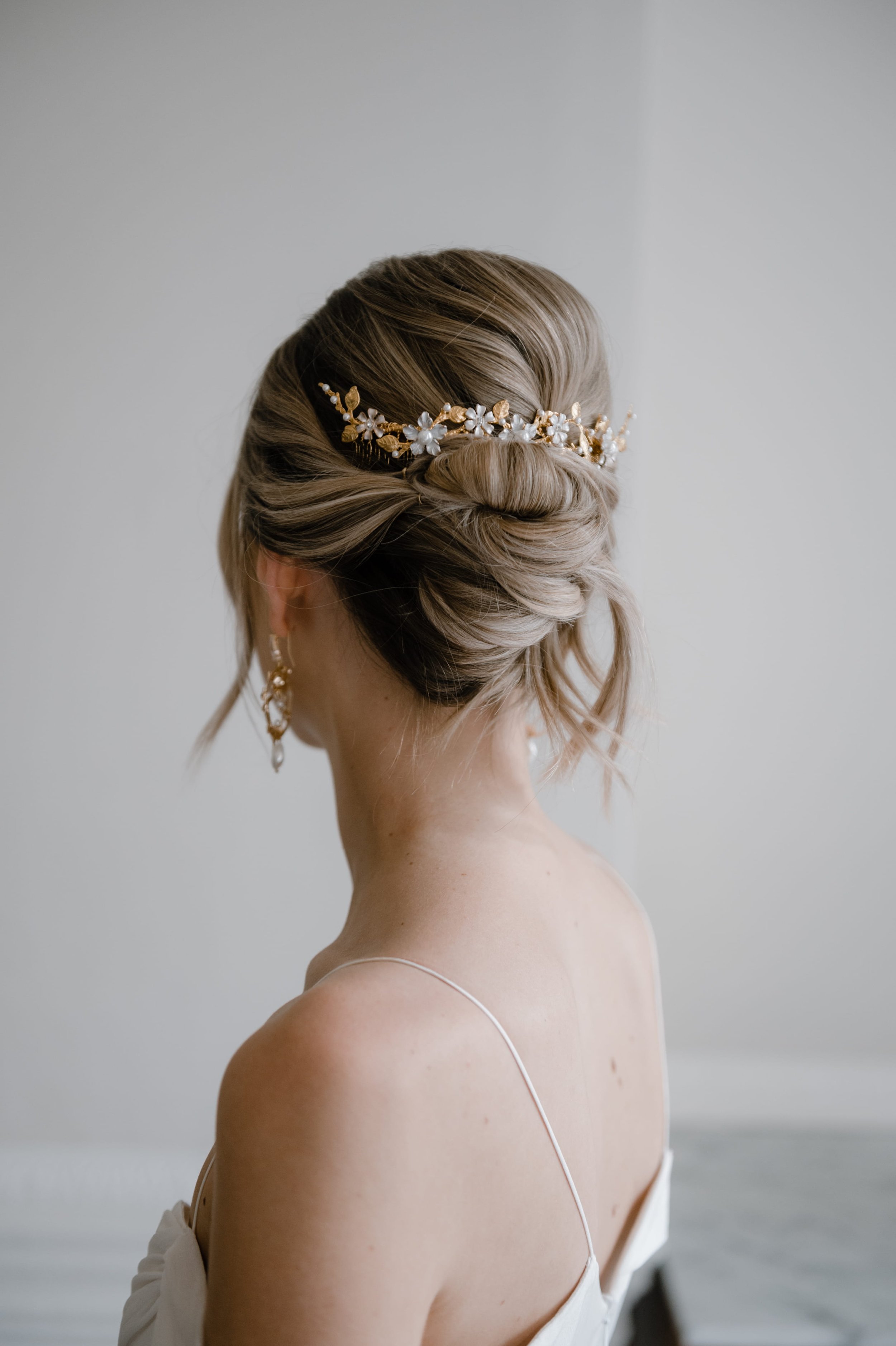 A bride photographed from behind, wearing her blonde hair in a relaxed, slightly messy, modern bridal updo, ready for her wedding day in London.