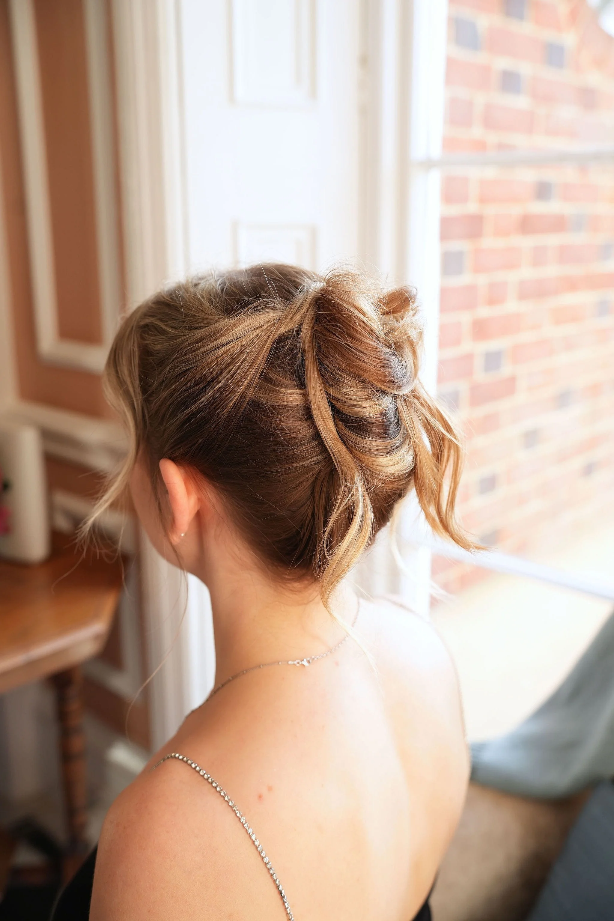 The back view of a relaxed, modern high piled updo created on fine hair.